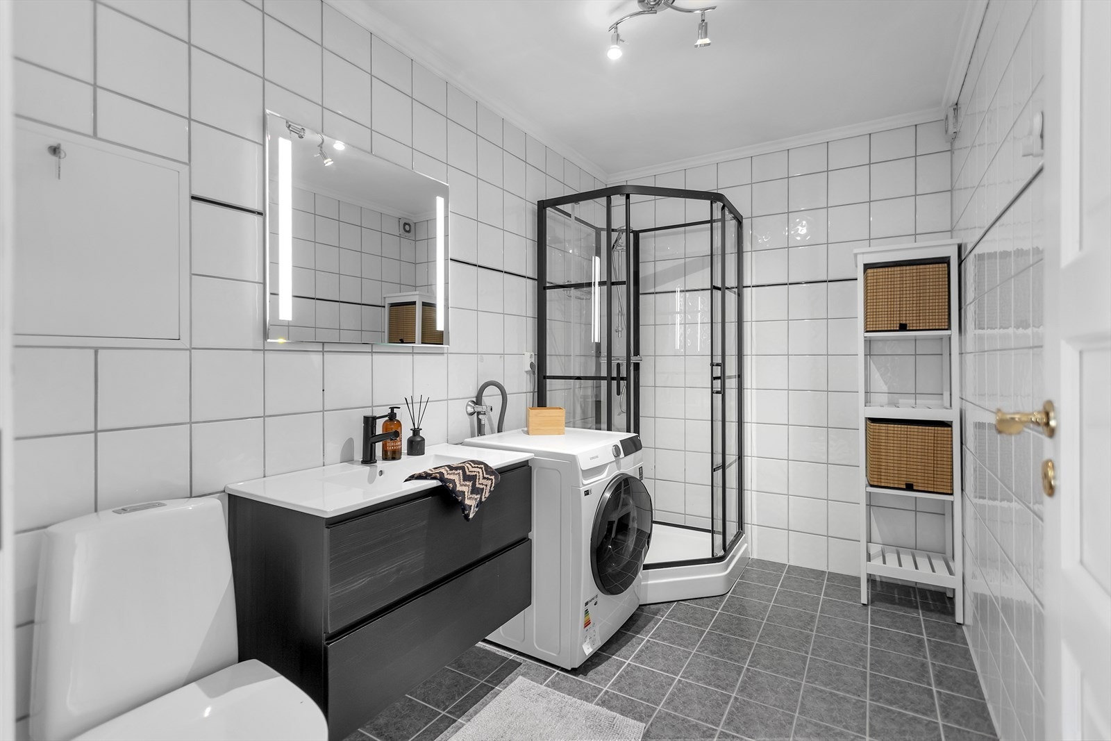 Lekkert helfliset baderom med moderne og praktiske løsninger. Badet er utstyrt med dusjkabinett, stilfullt speil med integrert belysning, samt en servant med underskuffer og toalett - begge fornyet i 2024. Det er opplegg for vaskemaskin og tørketrommel. Galleribilde