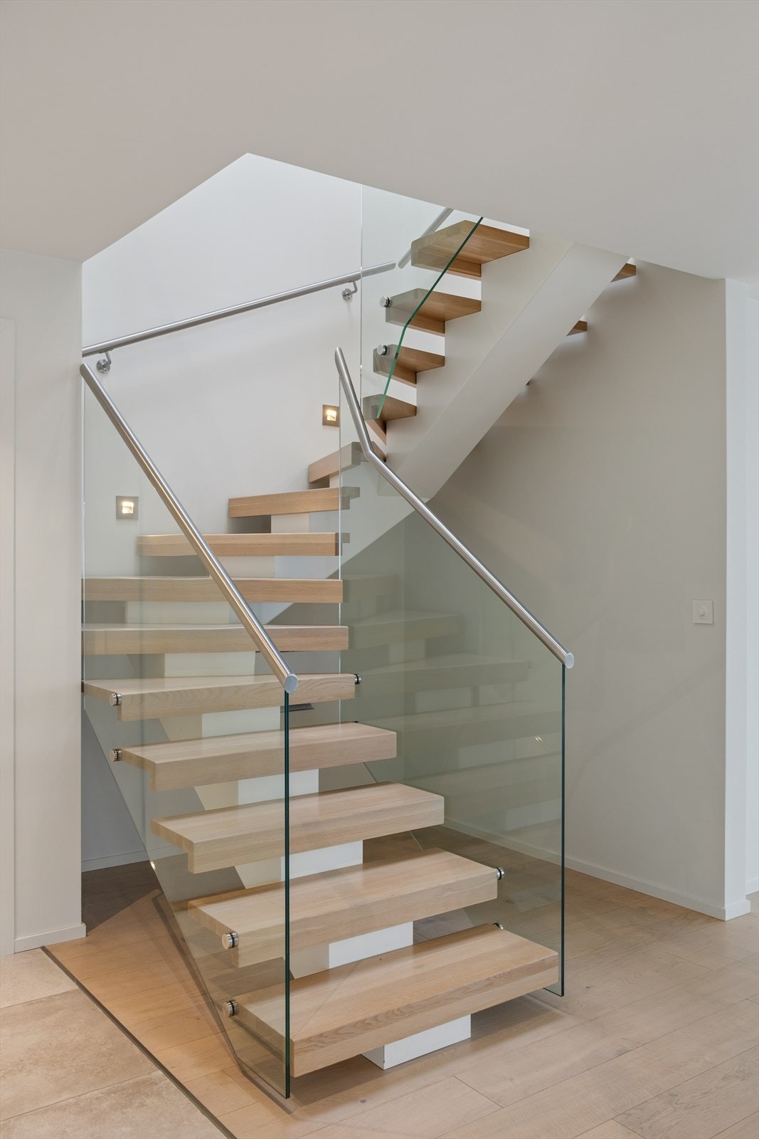 Moderne, påkostet trapp med åpne trinn, glassrekkverk og detaljer i tre og stål. Galleribilde