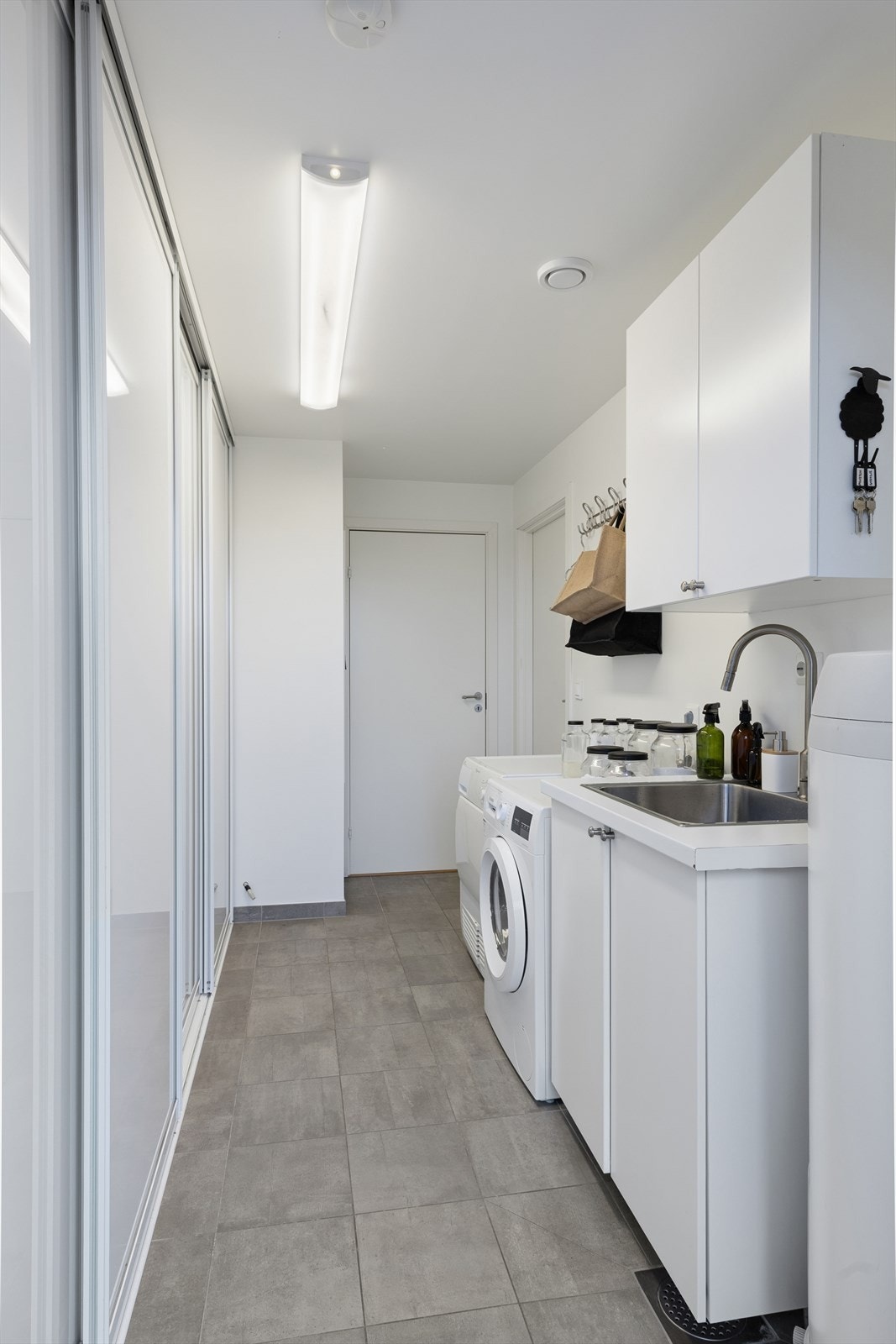 Eget vaskerom med opplegg for vaskemaskin og tørketrommel, og rikelig med skapplass. Galleribilde