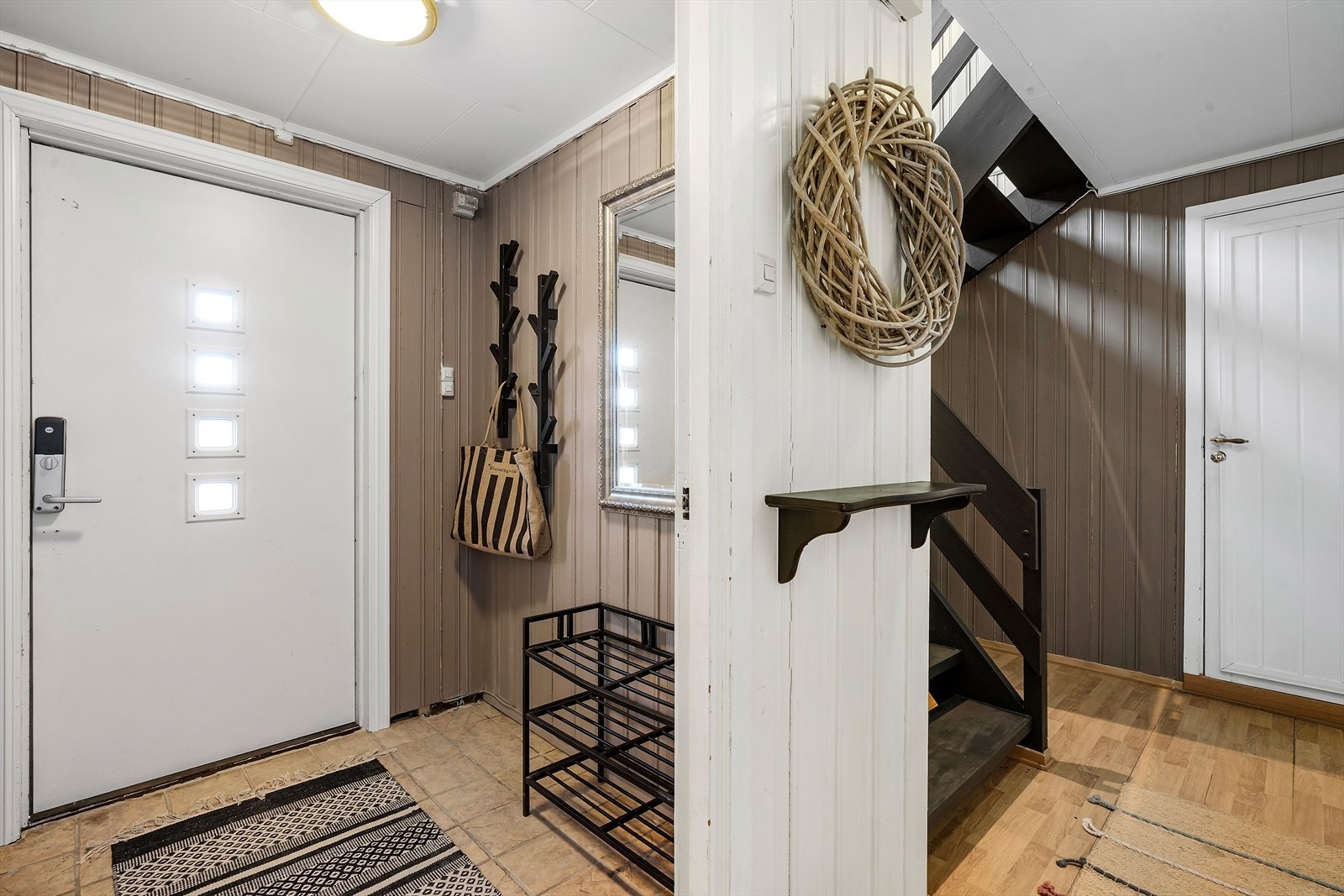 Flislagt gulv gir en praktisk og rengjøringsvennlig entré. Ytterdør med glassfelt slipper lys inn i rommet. Galleribilde