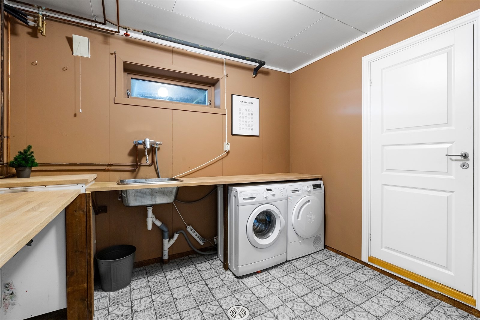 Vaskerommet har vinyl-belegg på gulvet og malte plater på veggene, med opplegg for vaskemaskin. Galleribilde