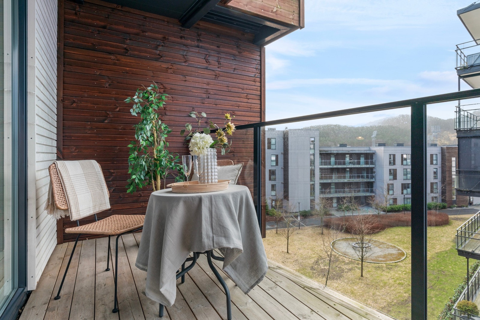 Terrassen har trykkimpregnerte terrassebord og høyt rekkverk i glass og metall Galleribilde