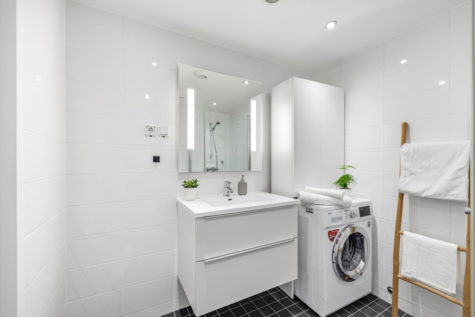 Innredningen er bestående av lyst servantskap med skuffer, speil med lys og opplegg for vaskemaskin. Galleribilde