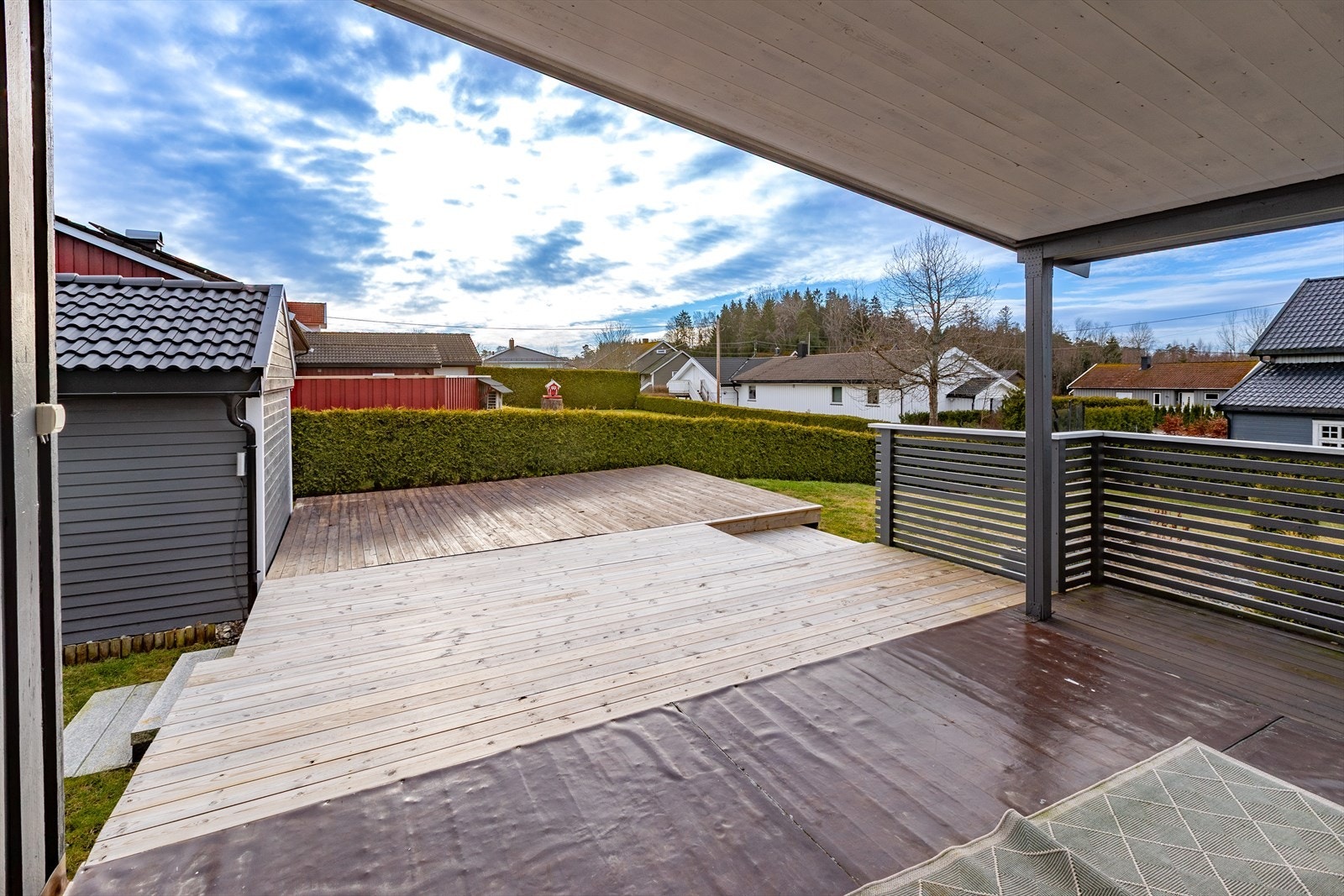 Utsikt fra terrassen gir oversikt over den opparbeidede tomten med plen og beplantning. Galleribilde