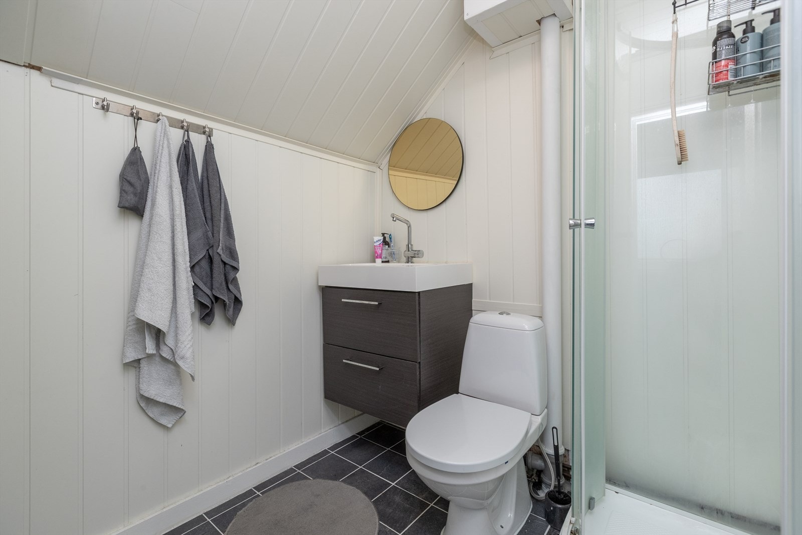 Badet er utstyrt med dusjkabinett og servant med underskap for praktisk bruk. Galleribilde