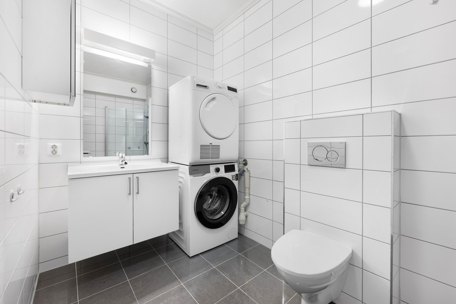Kjellerleilighet - Badet er helfliset med gulvvarme og innredet med baderomsmøbler, vegghengt wc og dusjhjørne Galleribilde