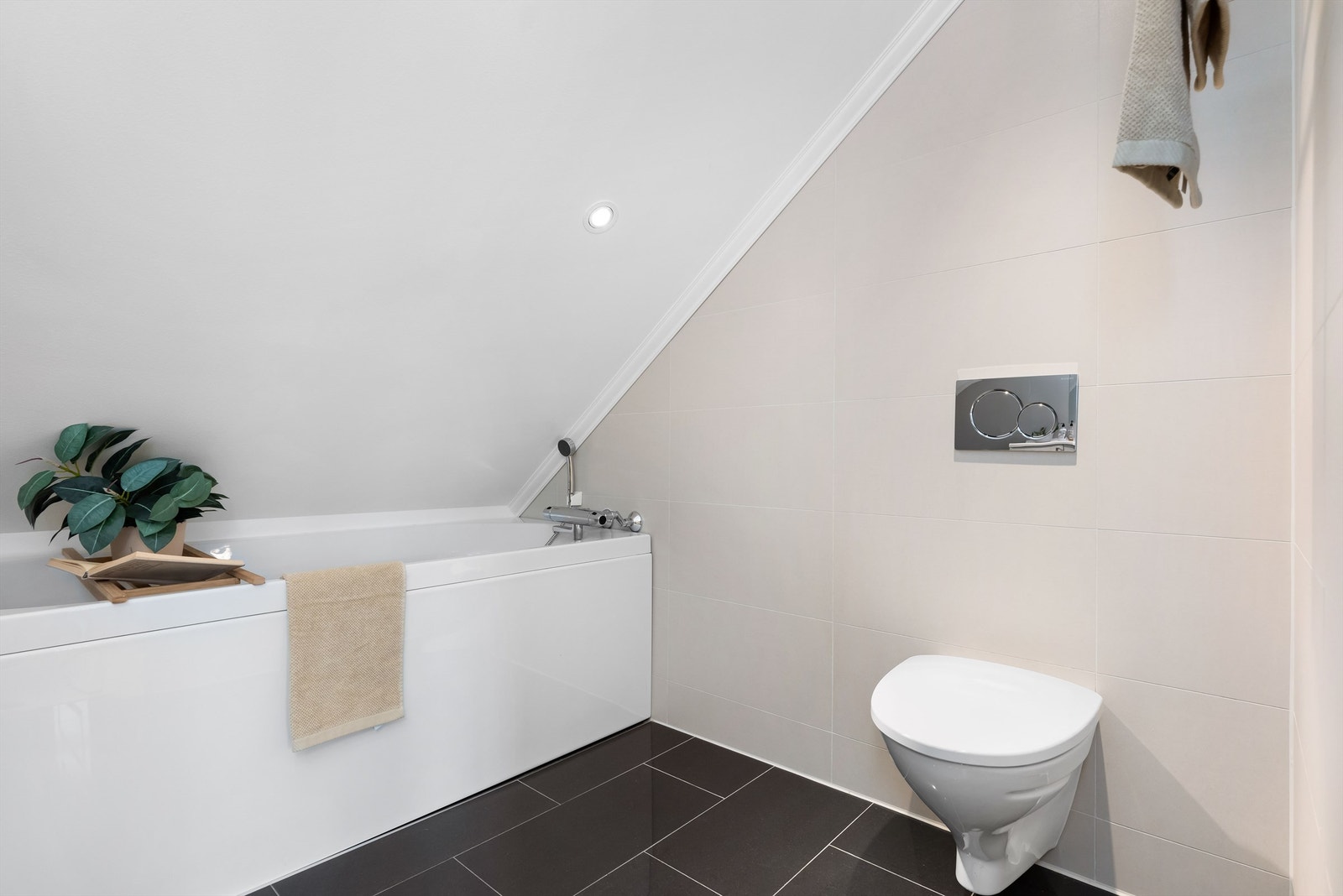 Badet er helfliset med varmekabler og innredet med baderomsmøbel, badekar og vegghengt wc Galleribilde