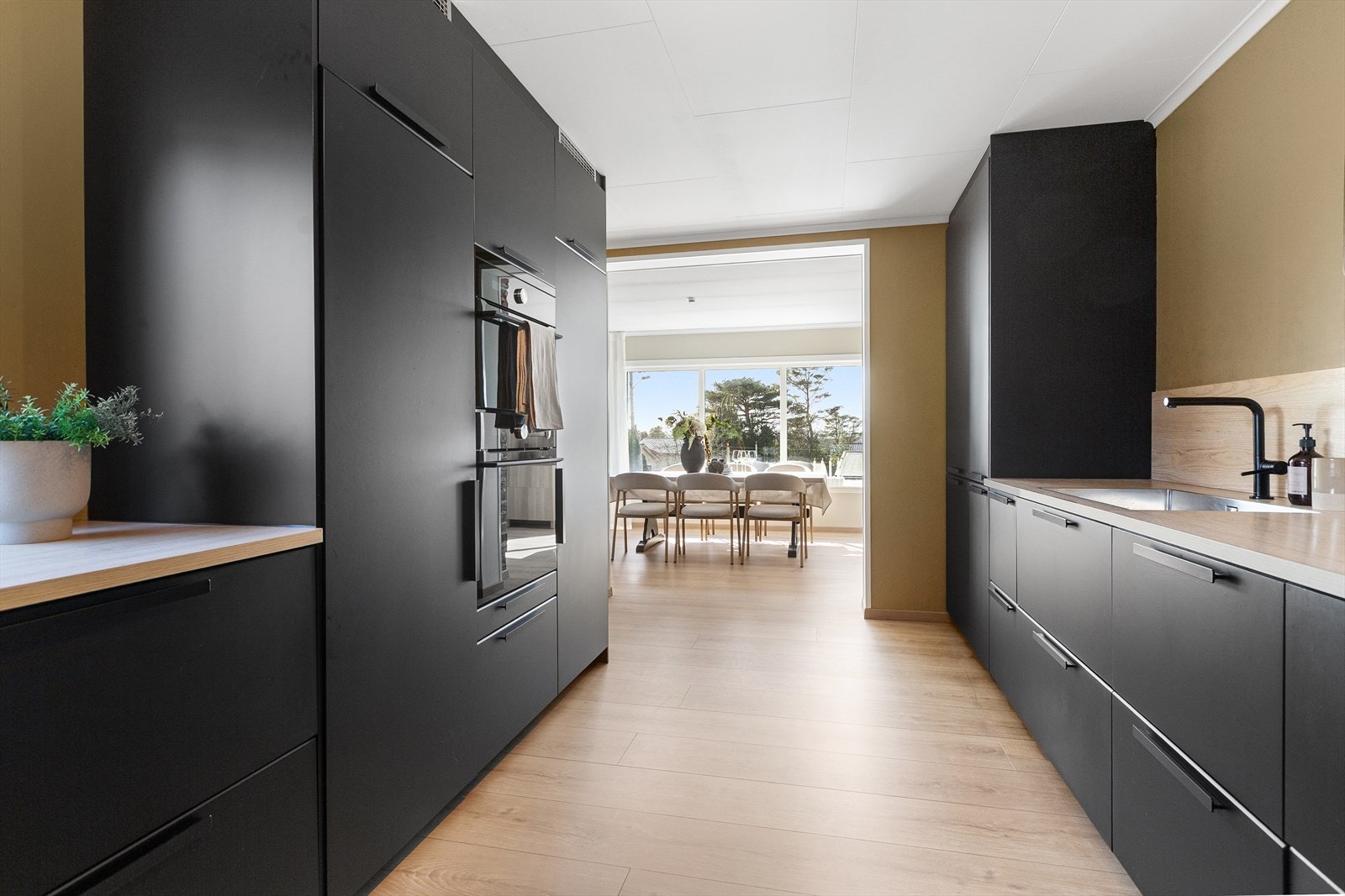 Flott og moderne kjøkkeninnredning med glatte, sorte fronter og benkeplate av laminat med nedfelt vask. Galleribilde