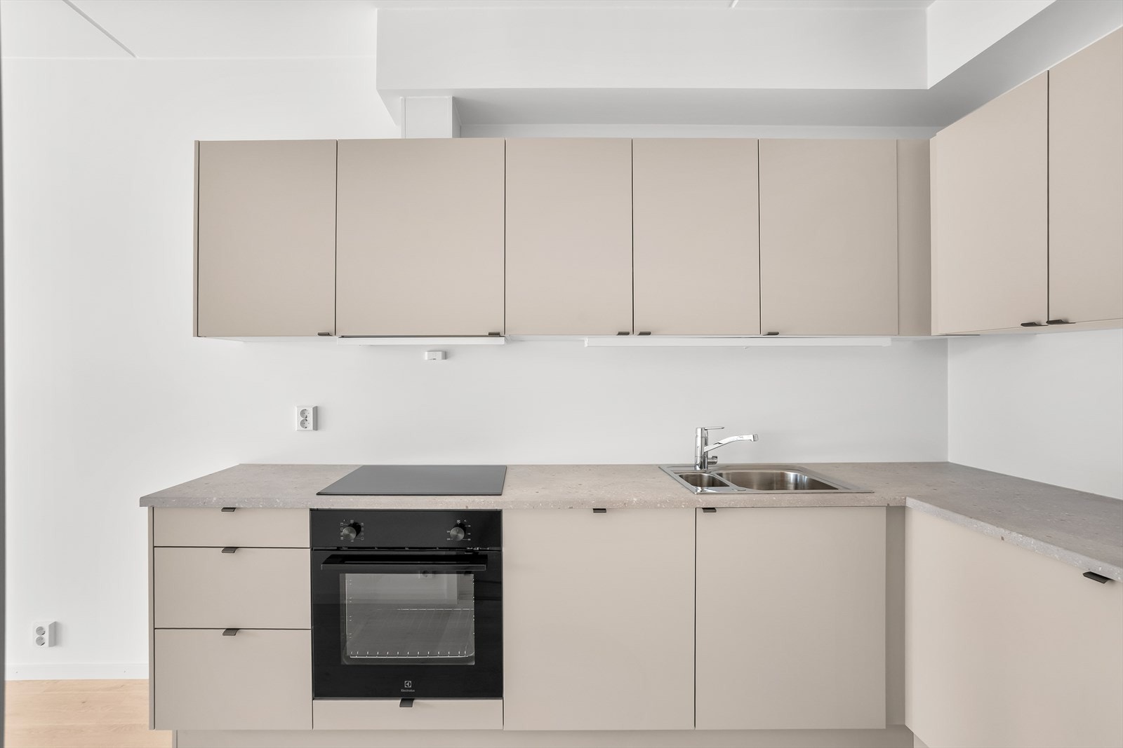Innredningen er moderne med slette, beige fronter, laminat benkeplate og belysning under overskap. Galleribilde