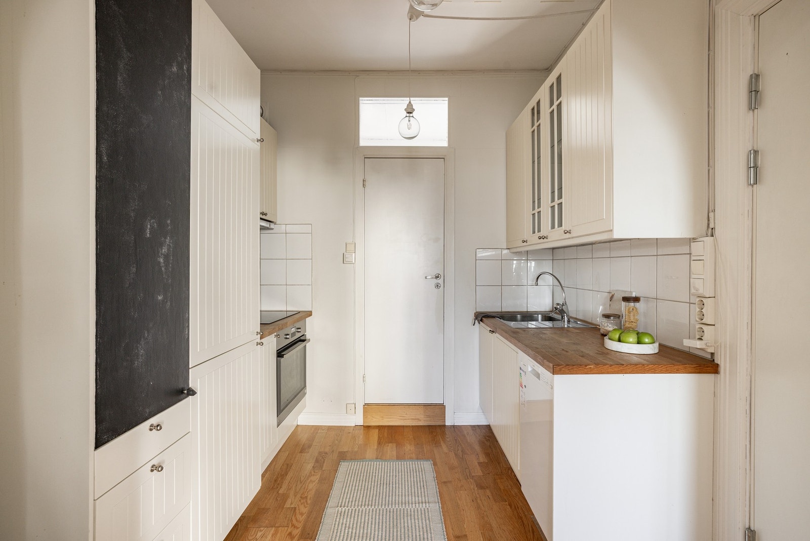 Tidløst kjøkken med hvit innredning og heltre benkeplate. Galleribilde