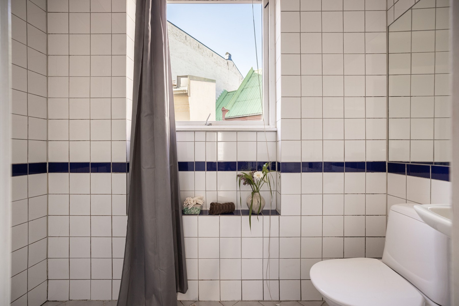 Flislagt baderom med praktisk vindu som gir naturlig lysinnslipp. Galleribilde