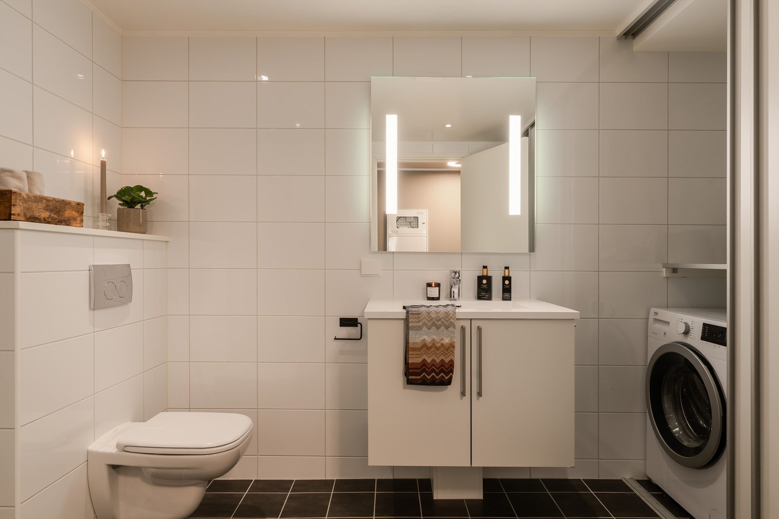 Badet har gulvvarme, downlights, vegghengt toalett og et dusjhjørne med innfellbare glassdører. Galleribilde