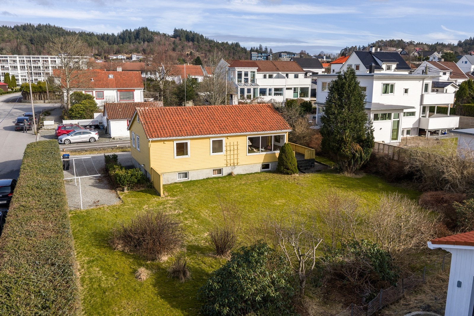 Tomten er forholdsvis flat og er godt skjermet bak en vintergrønn hekk Galleribilde