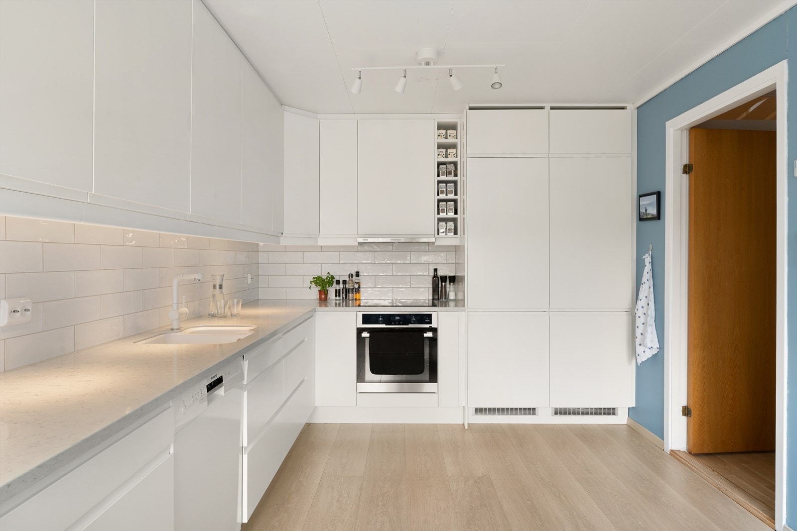 Romslig og moderne kjøkken med spiseplass. Hvit slett kjøkkeninnredning fra Epok, ny i 2019, med benkeplate i stein, fliser over benk og integrerte hvitevarer. Meget god skap og benkeplass. Galleribilde