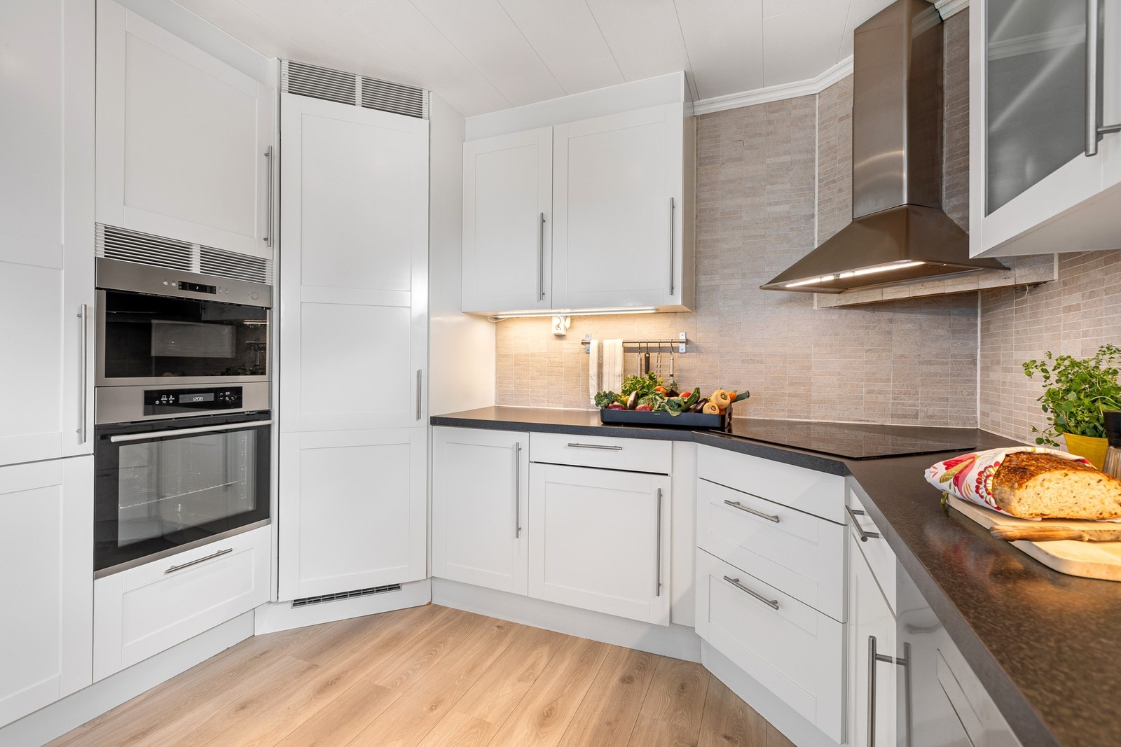 Romslig og tidløs innredning med integrert platetopp, komfyr og micro i høyskap Galleribilde