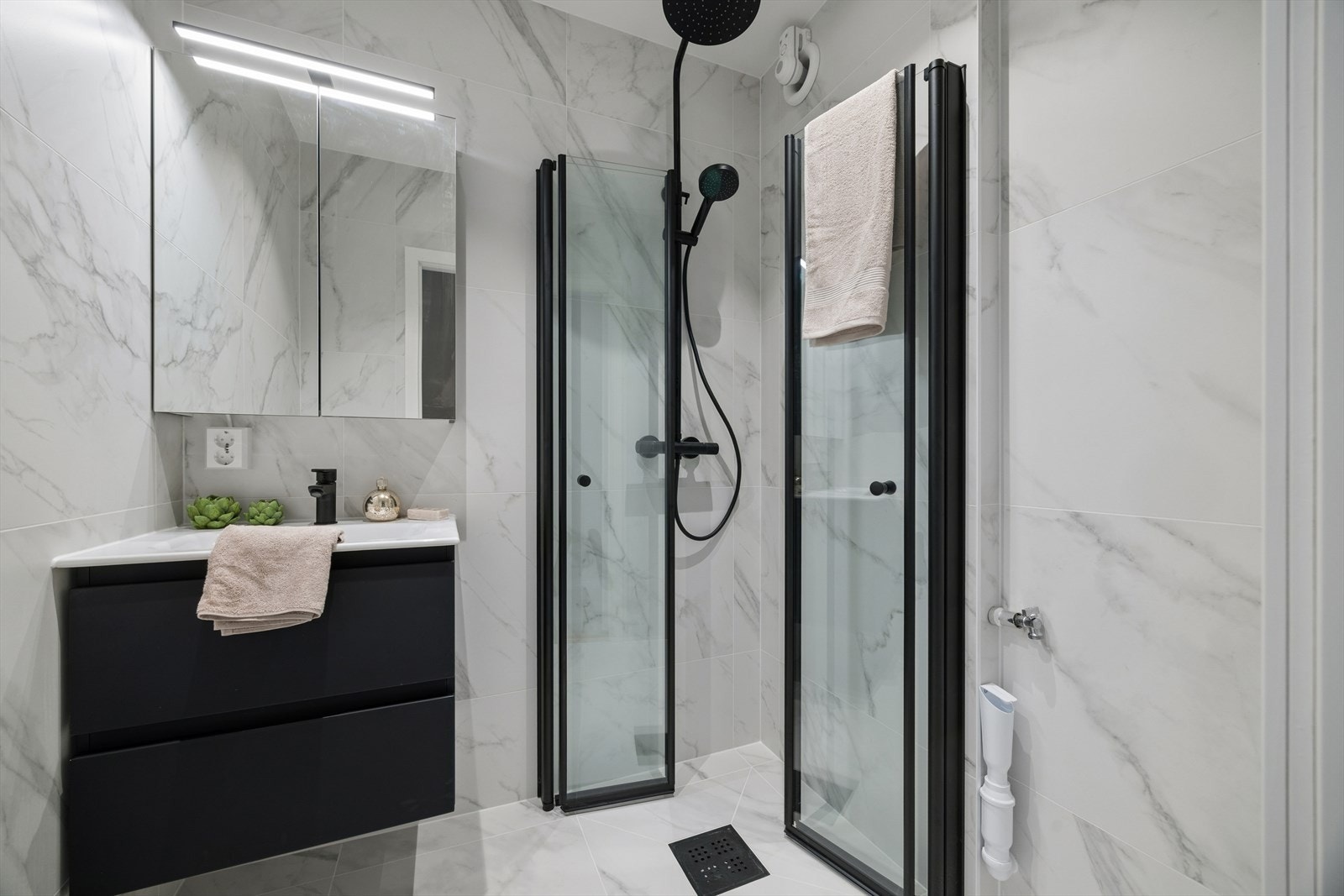 Badet ble totalrenovert i 2026 med flislagte overflater, dusjvegger i glass og opplegg for vaskemaskin. Galleribilde