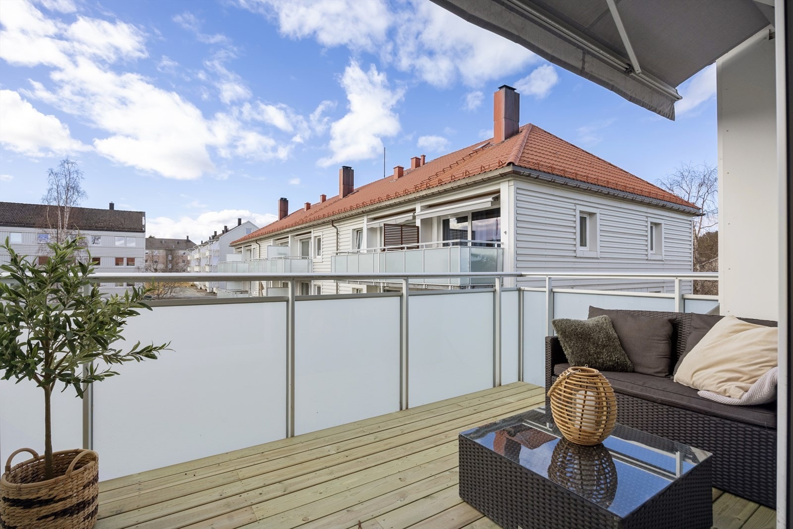 Balkongen har terrassebord i impregnerte materialer og utsikt mot borettslagets fellesarealer. Galleribilde