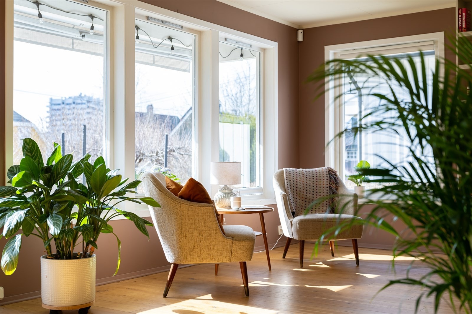 Lyst hjørne i stuen med store vinduer og utsikt mot hagen, perfekt for rolige stunder Galleribilde