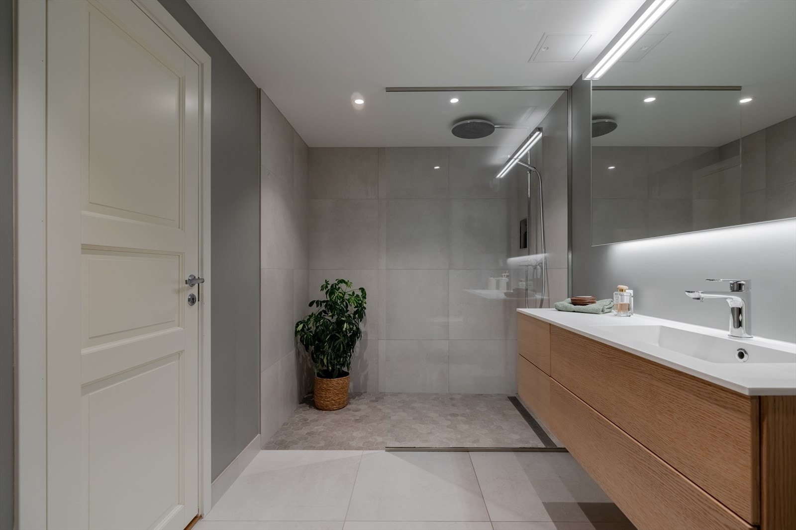 Badet har flislagt gulv og fliser på vegg i dusjsonen samt sokkelflis på vegg, ellers malte flater på vegger og malte plater i himling Galleribilde