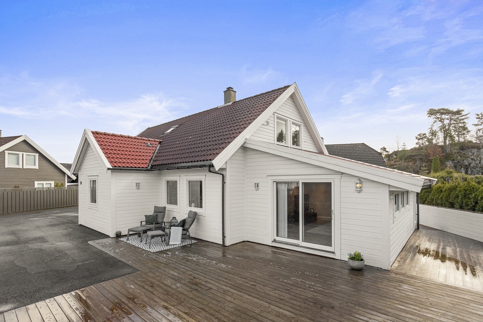 Flat og fin tomt med treterrasse, kunstgress og stor, asfaltert gårdsplass. Galleribilde