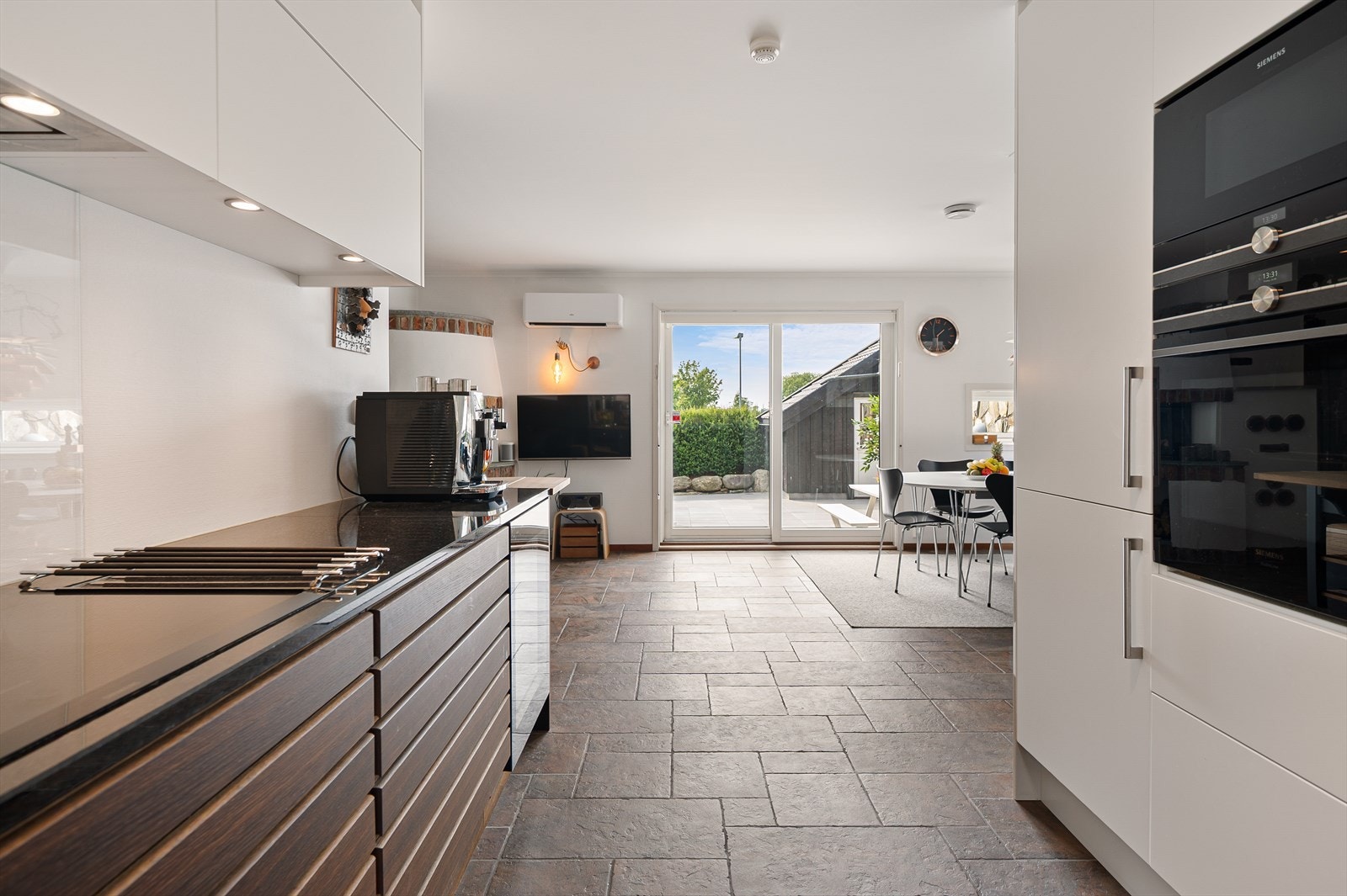 Innredningen har med underskap i mørkt treverk med horisontale linjer, og overskap med glatte, hvite fronter samt benkeplate av stein. Galleribilde