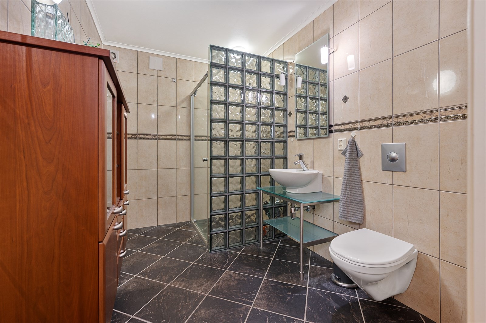 Badet er utstyrt med innredning med nedfelt servant, toalett og dusjvegger/hjørne. Galleribilde