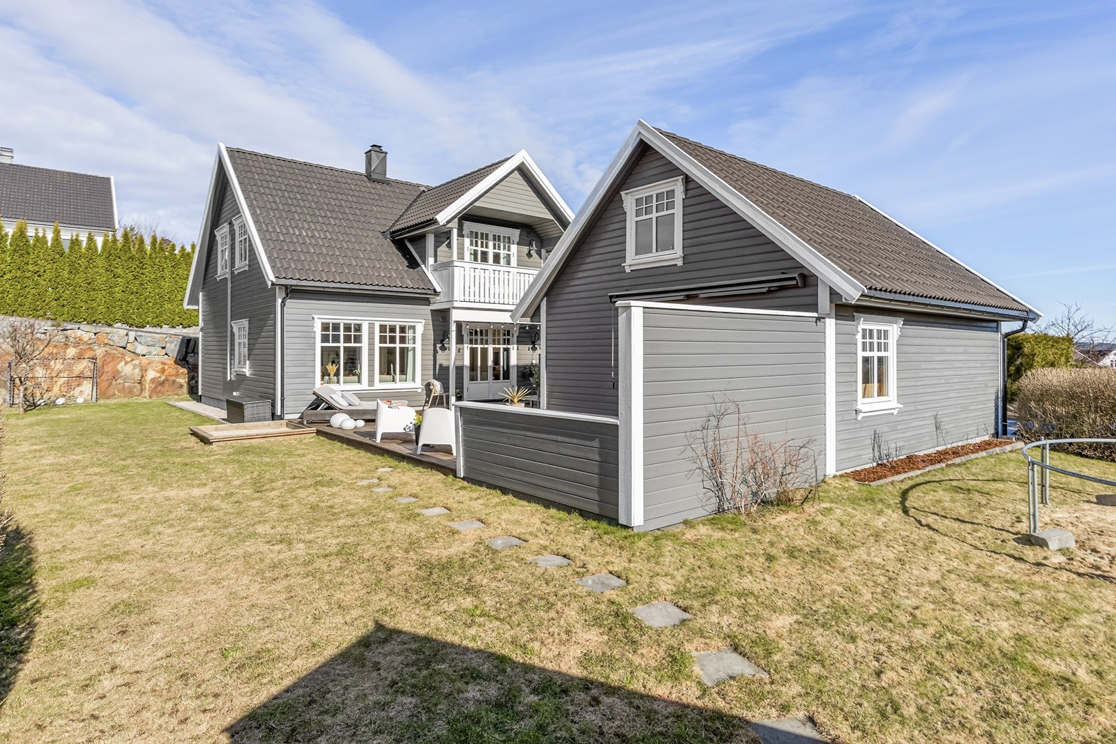 Romslig uteområde med terrasse og hage innrammet med hekk Galleribilde