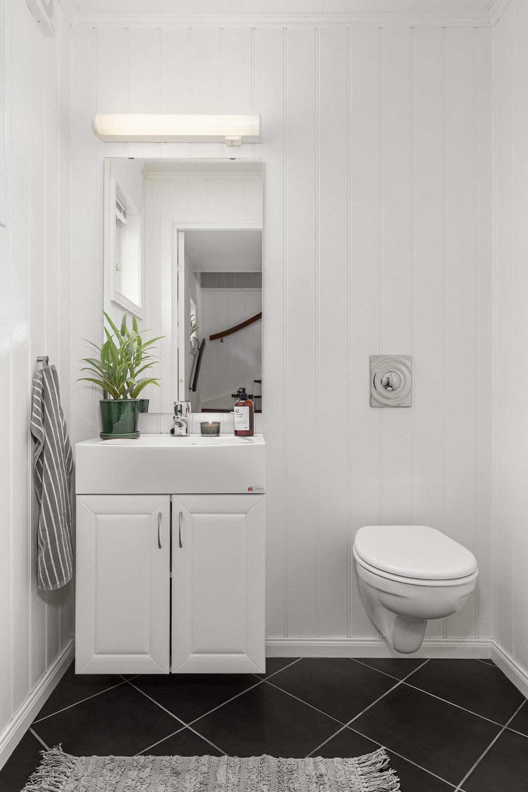 Toalettrommet har flislagt gulv og er innredet med servant, speil og toalett Galleribilde