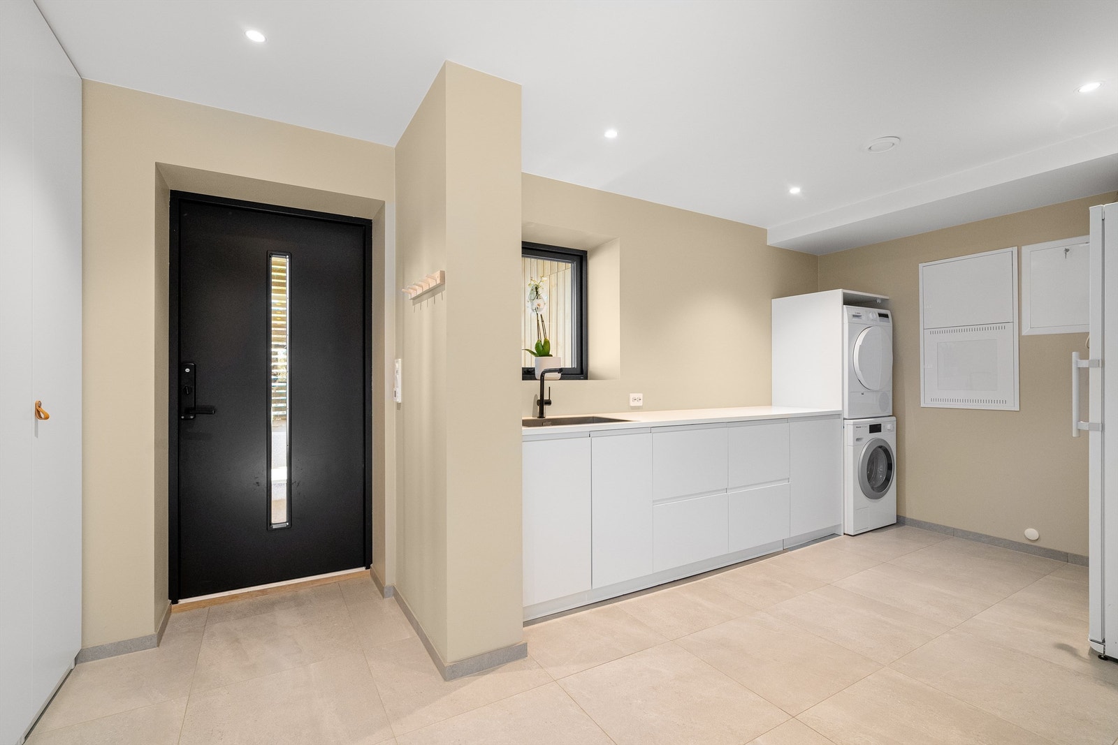 Det er romslig og praktisk vaskerom med plass til både vaskemaskin og tørketrommel. Rikelig med oppbevaring i skuffer og arbeidsplass på benk, utslagsvask, spotter i tak. Galleribilde