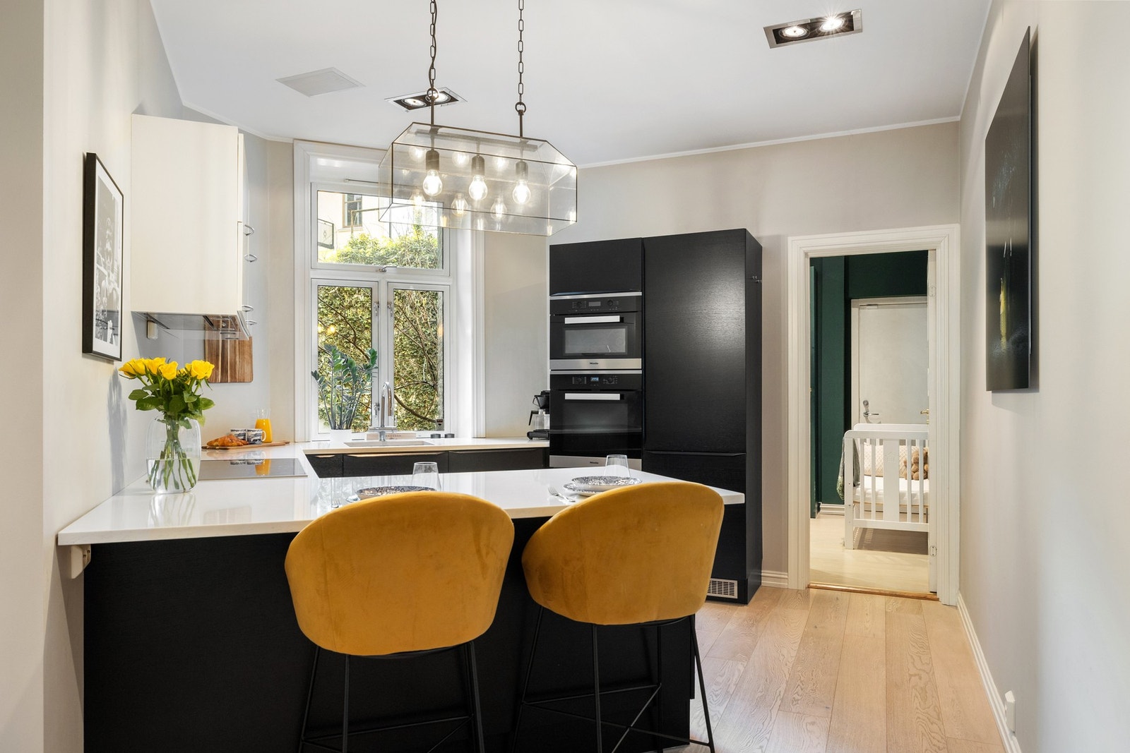 Halvøyen gir ekstra benkeplass og har sitteplasser, noe som skaper en naturlig samlingsplass i rommet. Hyggelig utsyn i grønn og beplantet bakgård Galleribilde