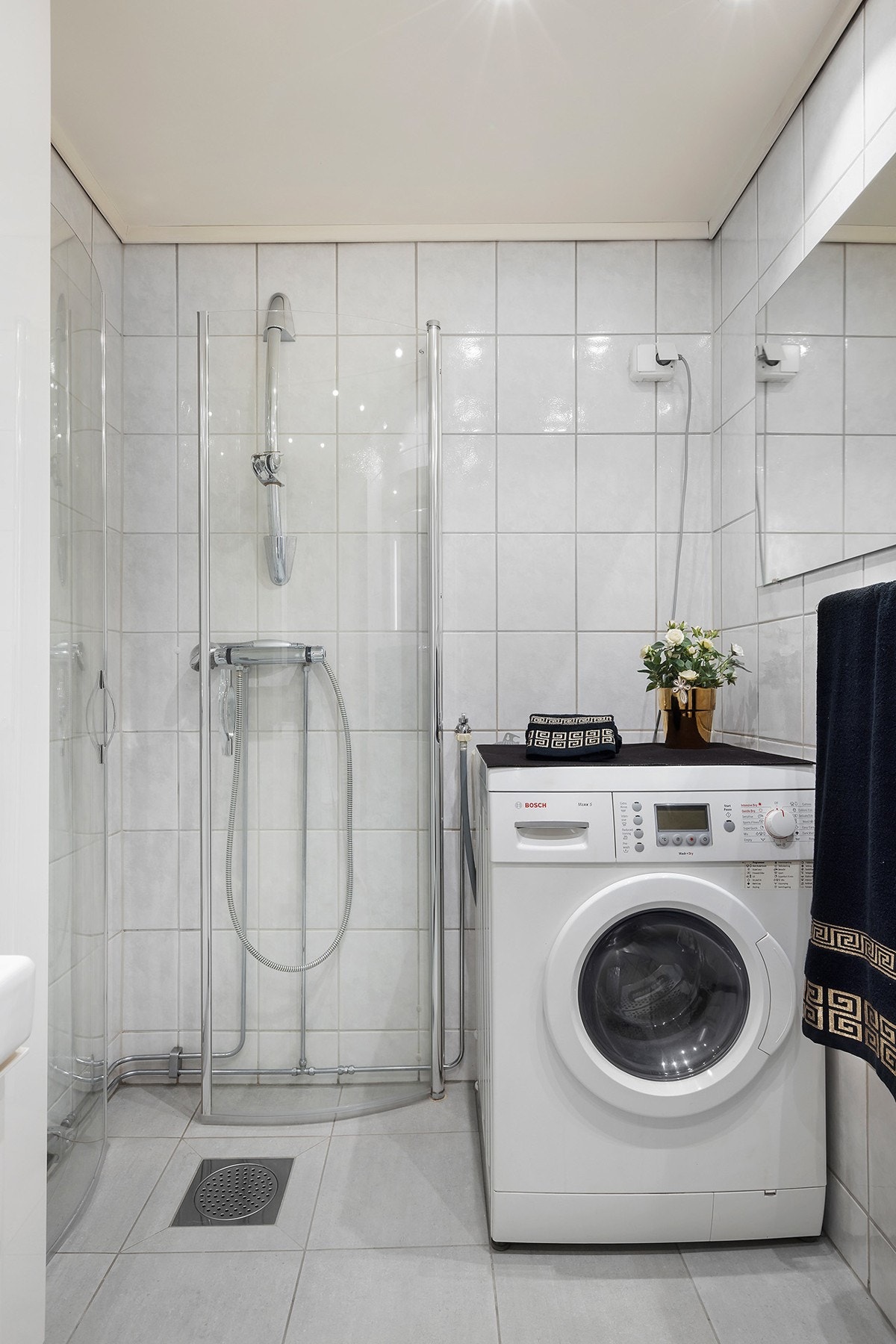 Badet er utstyrt med servant med skuffeseksjon, speilskap med sidelys, gulvmontert klosett, veggskap og dusjhjørne med svingbare glassdører. Opplegg for vaskemskin. Galleribilde