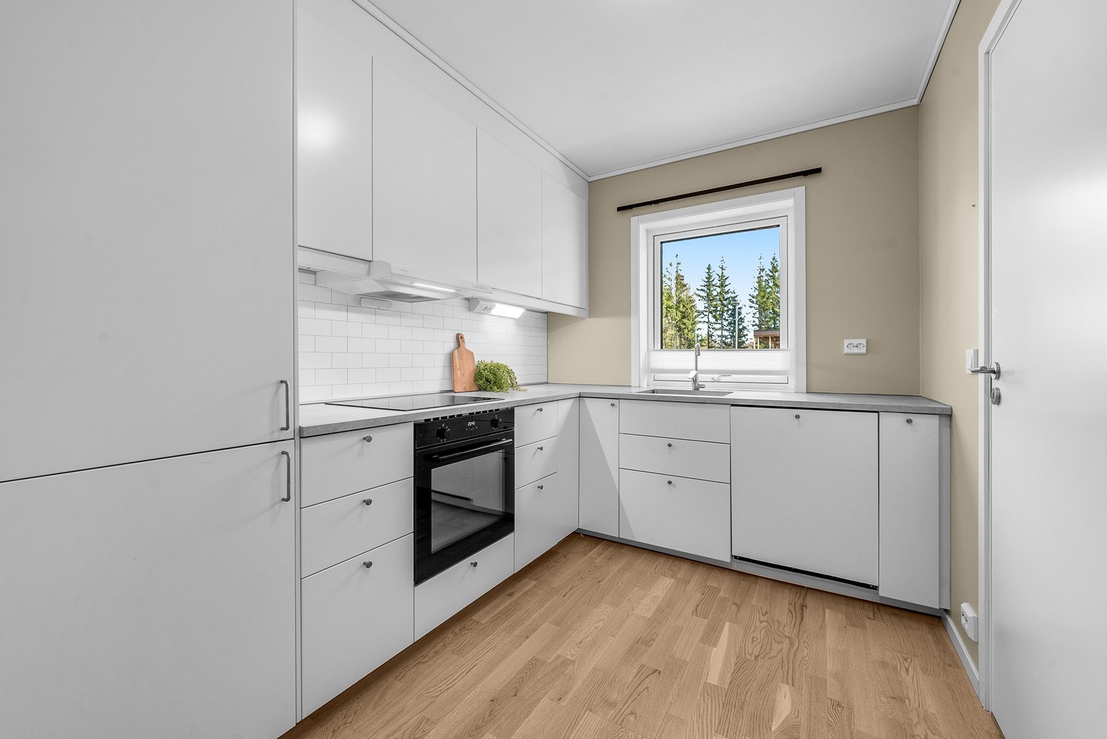 Kjøkkenet har en moderne innredning med hvite, glatte fronter og laminatbenkeplate. Galleribilde