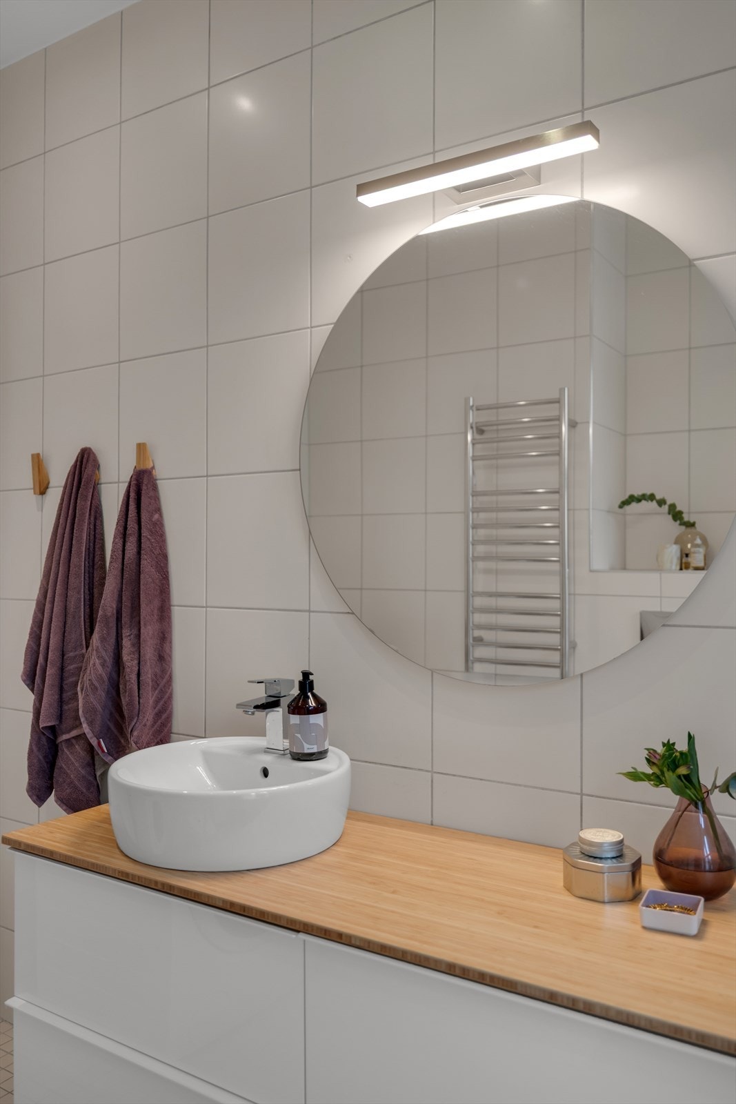 Badet inneholder vegghengt servantinnredning (ny i 2019) med benkeplate av treverk og ovenpåliggende servant. Stort og moderne speil, vegghengt skap, innebygget badekar med ovenpåliggende glassdør og vegghengt toalett. Galleribilde
