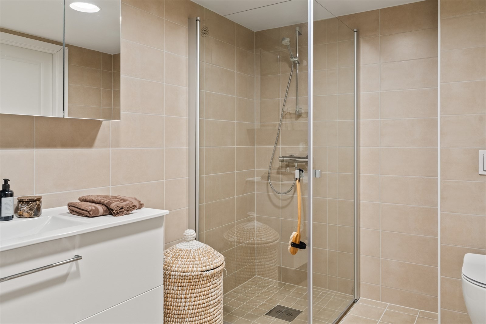 Badet inneholder baderomsinnredning med nedfelt servant, høyskap, vegghengt toalett og dusjhjørne Galleribilde