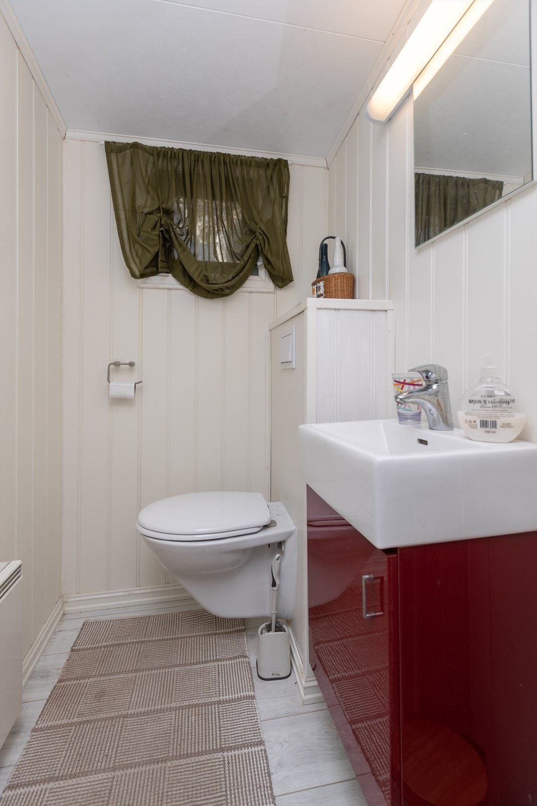 Badet har vegger med panel og et gulv dekket av fliser. Galleribilde