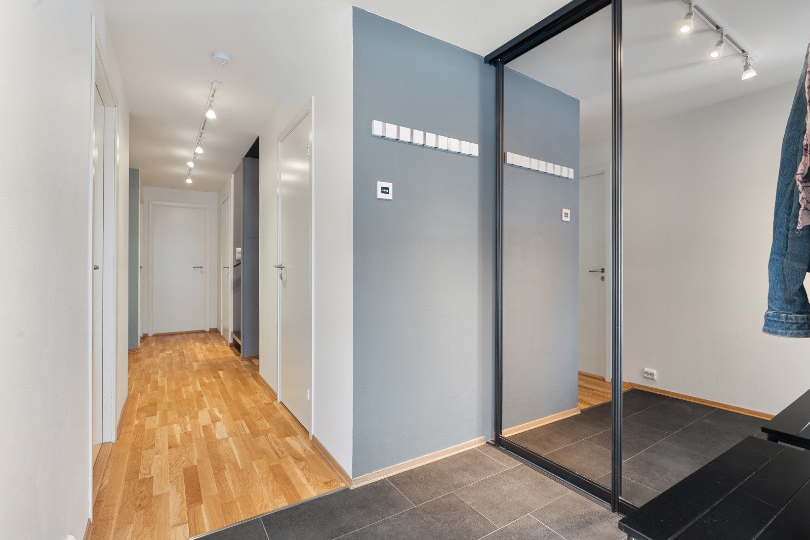 Romslig entré med fliser på gulv, gulvvarme og en praktisk skyvedørsgarderobe med speildører