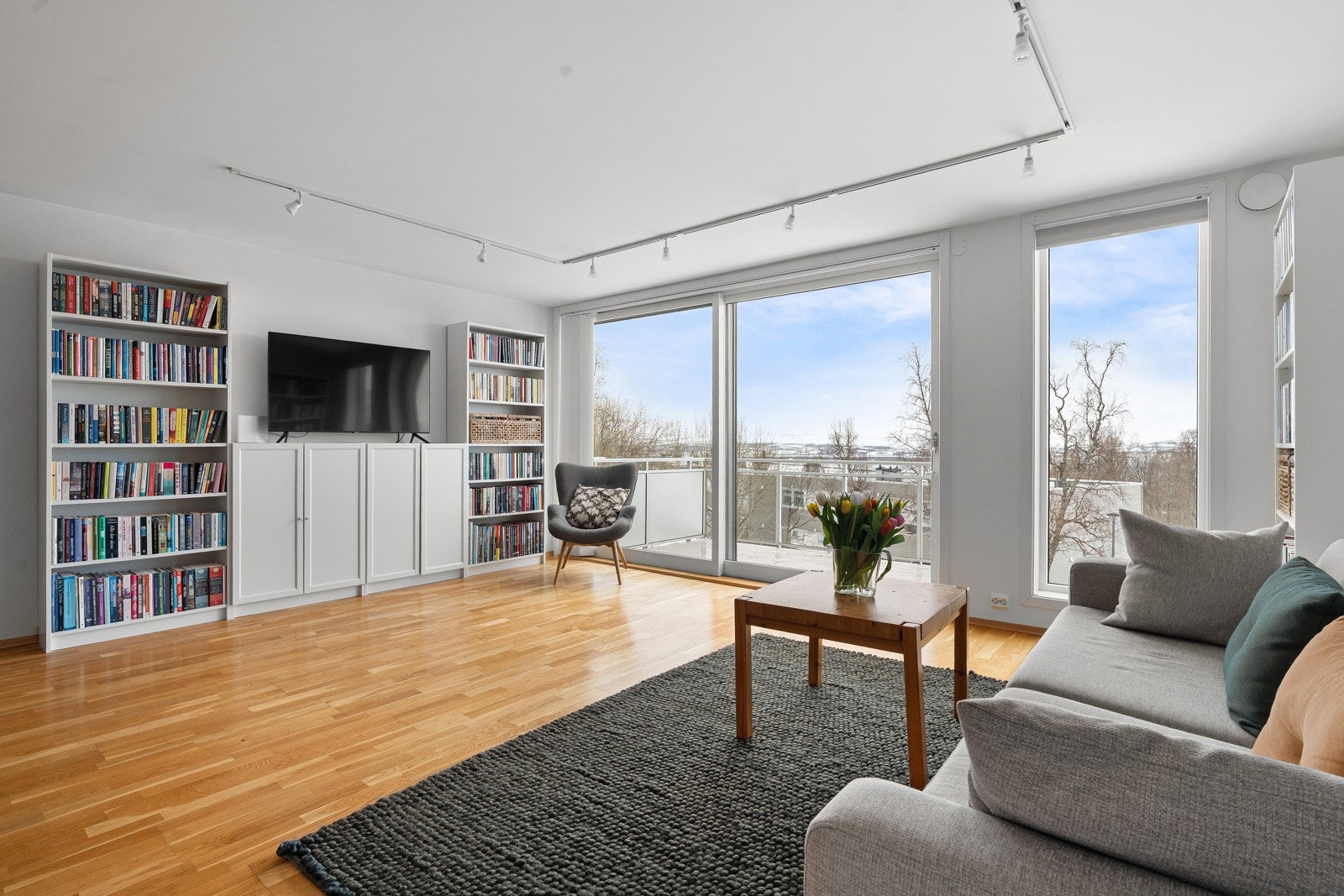 Lys og innbydende stue med malte veggoverflater og parkettgulv som gir et moderne og tidløst uttrykk.