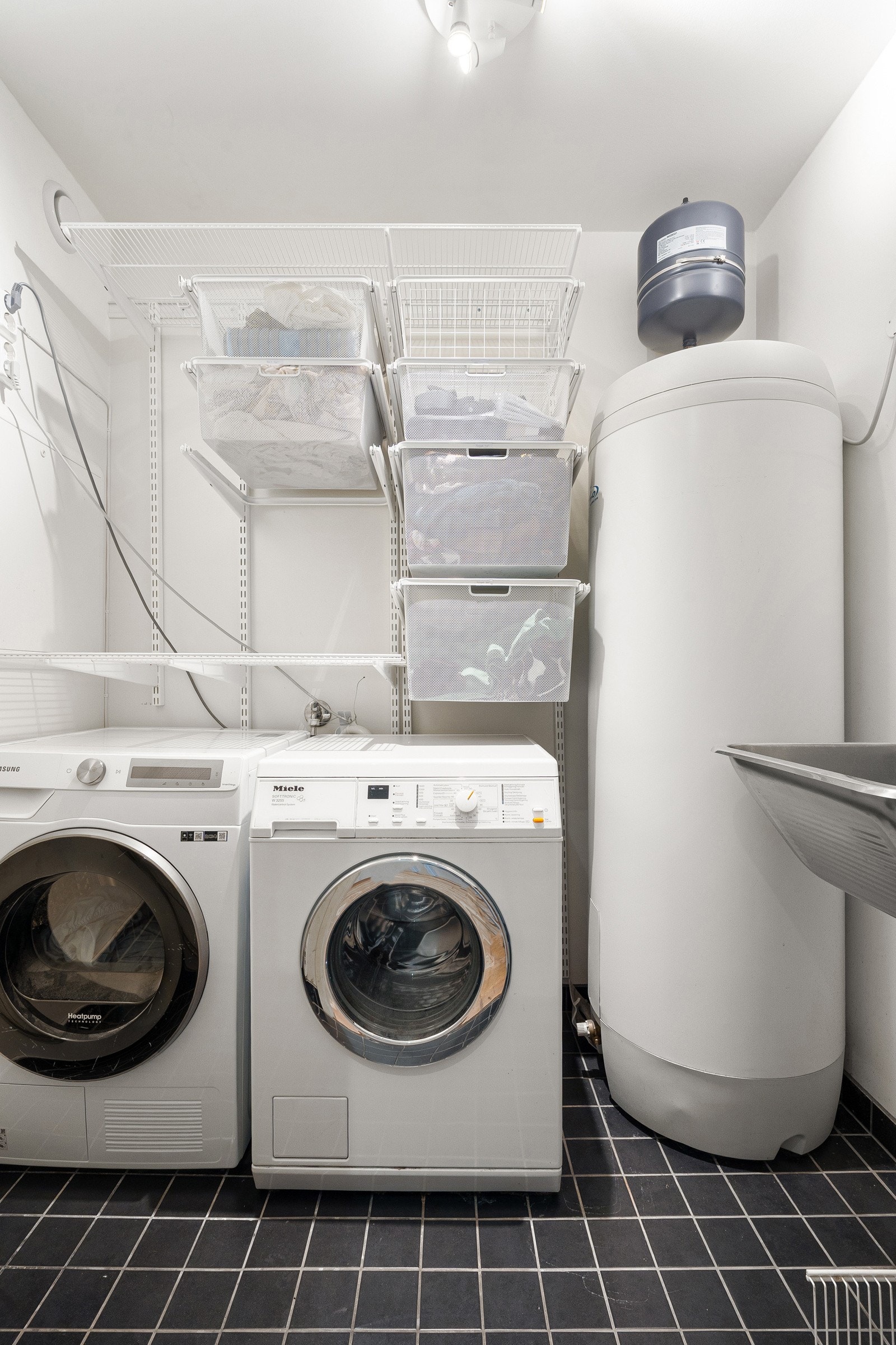 Separat vaskerom med fliser på gulv, gulvvarme, skyllekum og opplegg for vaskemaskin.