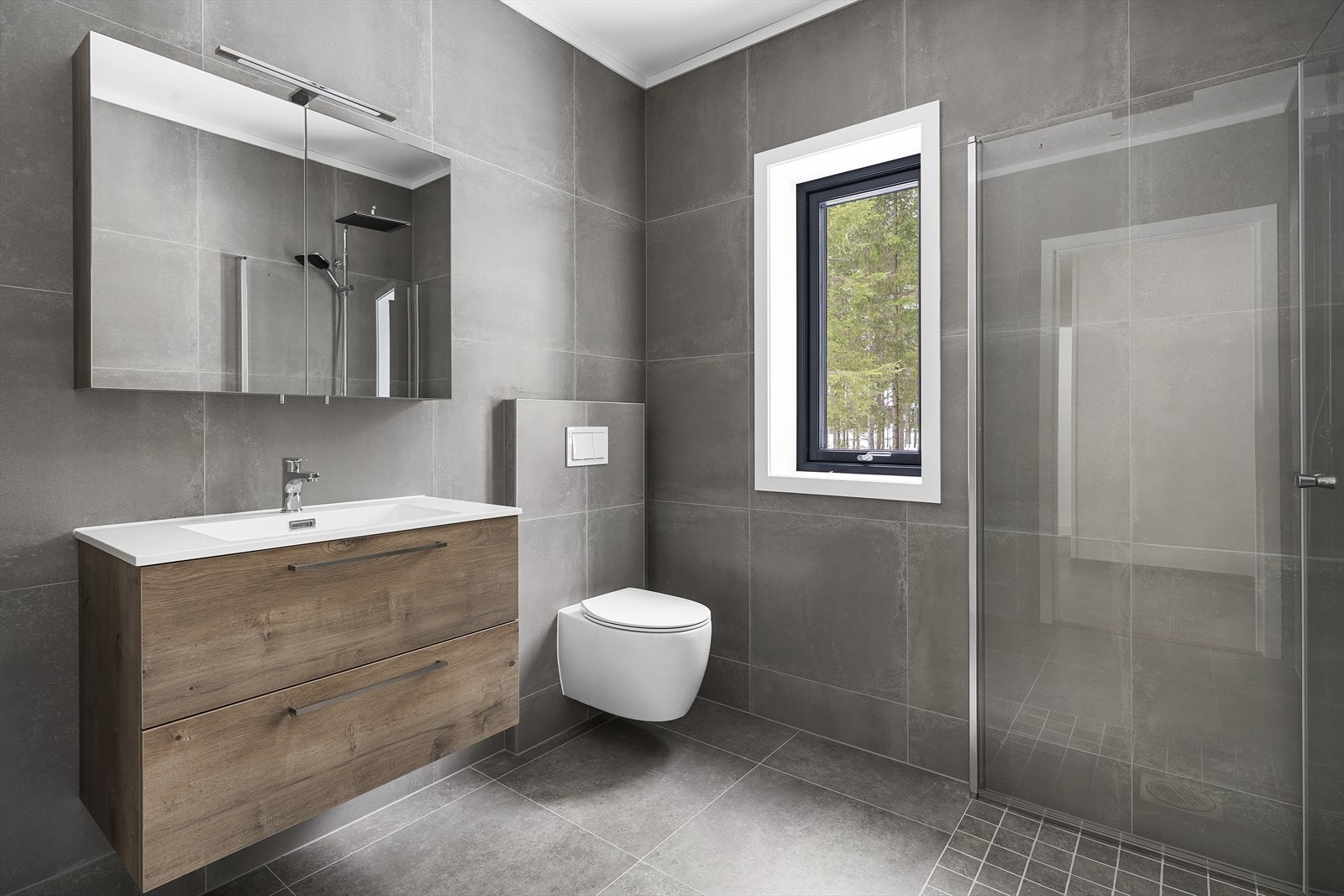 Badet er utstyrt med servantinnredning, vegghengt toalett og dusjløsning med glassvegger. Galleribilde