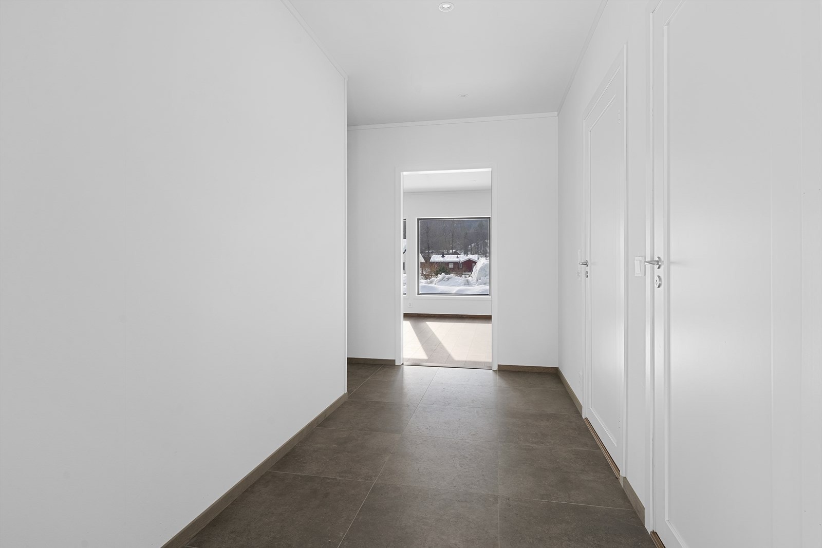 Fra overbygget inngangsparti kommer man inn i en lys og romslig entré med flislagt gulv og varmekabler som gir en komfortabel velkomst. Galleribilde