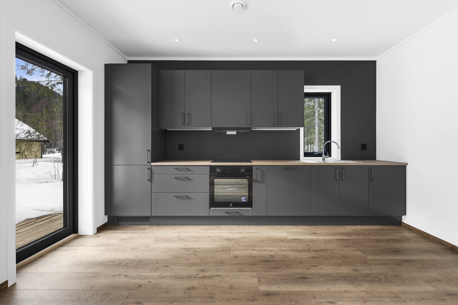 Kjøkkenet har stilren innredning med glatte fronter i mørk grå farge og gode arbeidsflater. Galleribilde