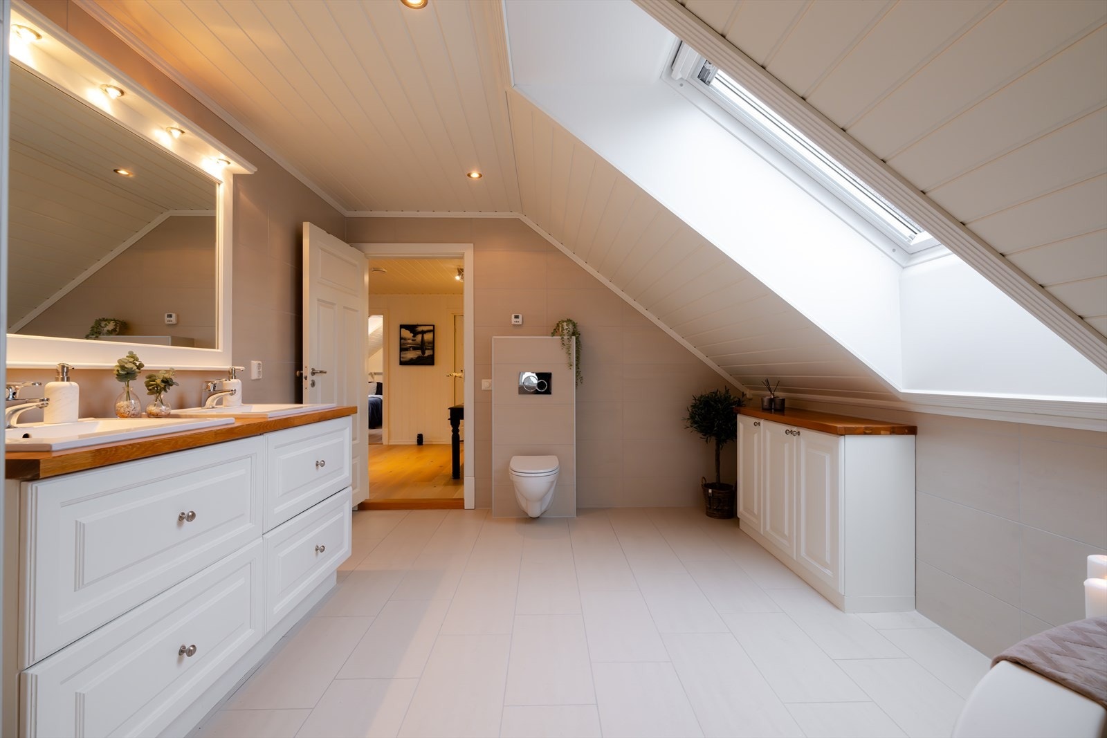 Herskapelig hovedbad med elegant design. Innredning med benkeskap, vegg- og høyskap med profilerte fronter, dusjnisje, badekar for ekstra velvære, dobbel servant, vegghengt toalett og praktisk klessjakt til vaskerom, funksjonelt og luksuriøst. Galleribilde