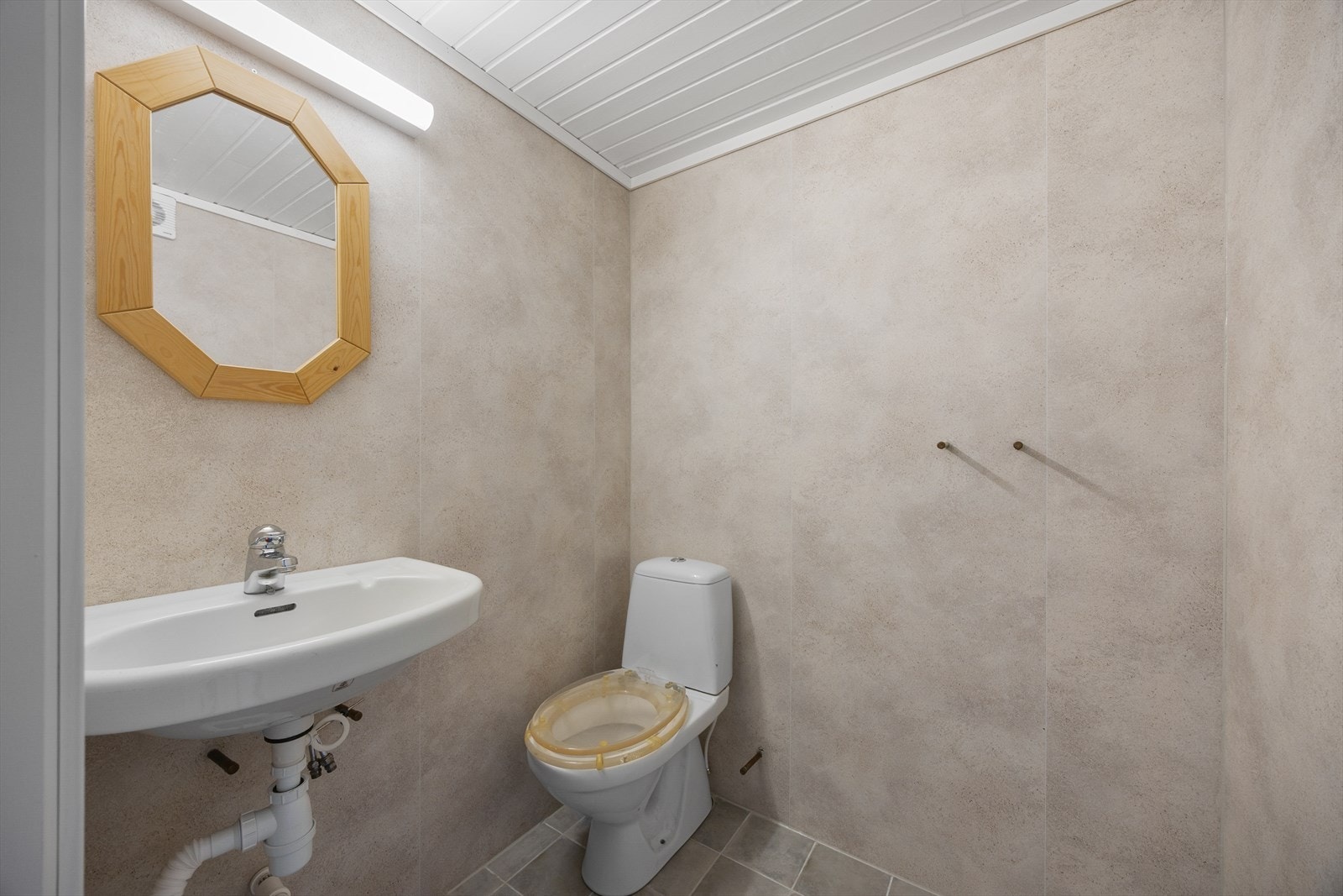 Badet innehar toalett, dusj og servant på vegg. Galleribilde