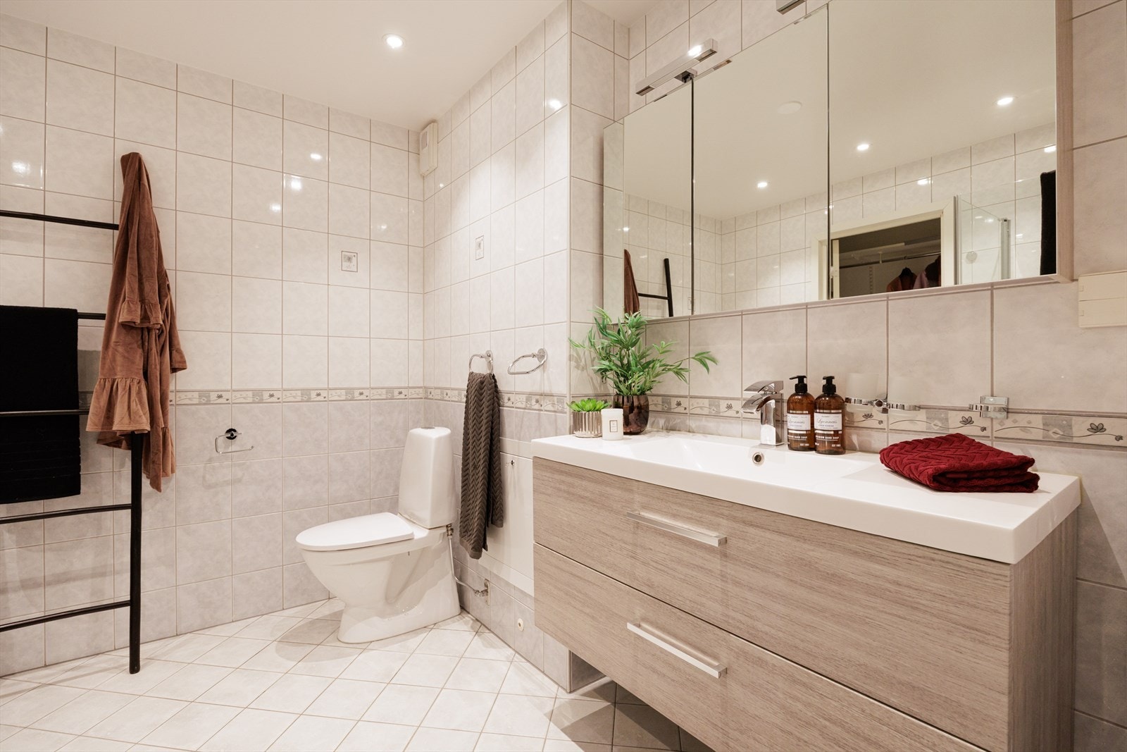 Badet er utstyrt med dusj med innfellbare glassdører, servant, gulvstående toalett og opplegg for vaskemaskin. Galleribilde