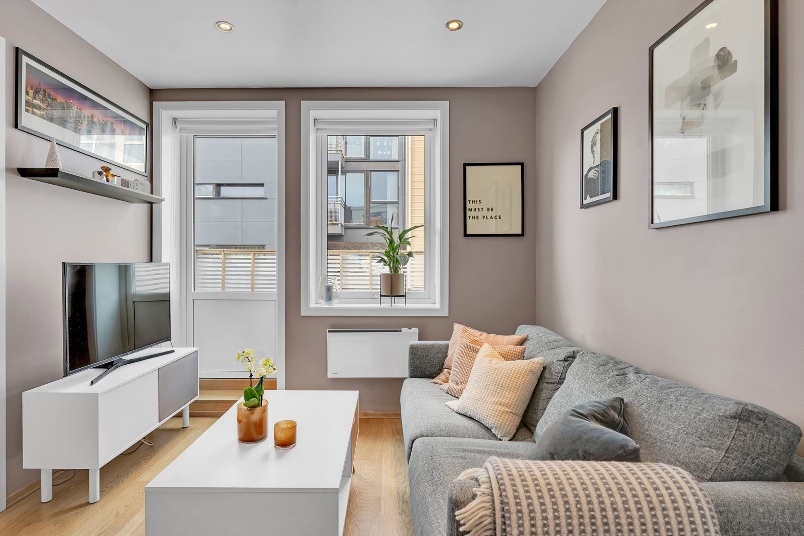 Stue med lekkert parkettgulv, glatte overflater i et lunt fargevalg og downlights i himling. Galleribilde