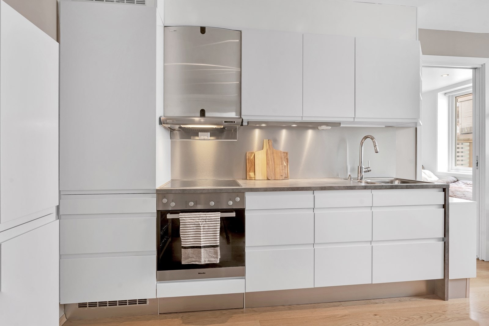 Moderne og flott kjøkken i hvit utførelse med integrerte hvitevarer. Galleribilde