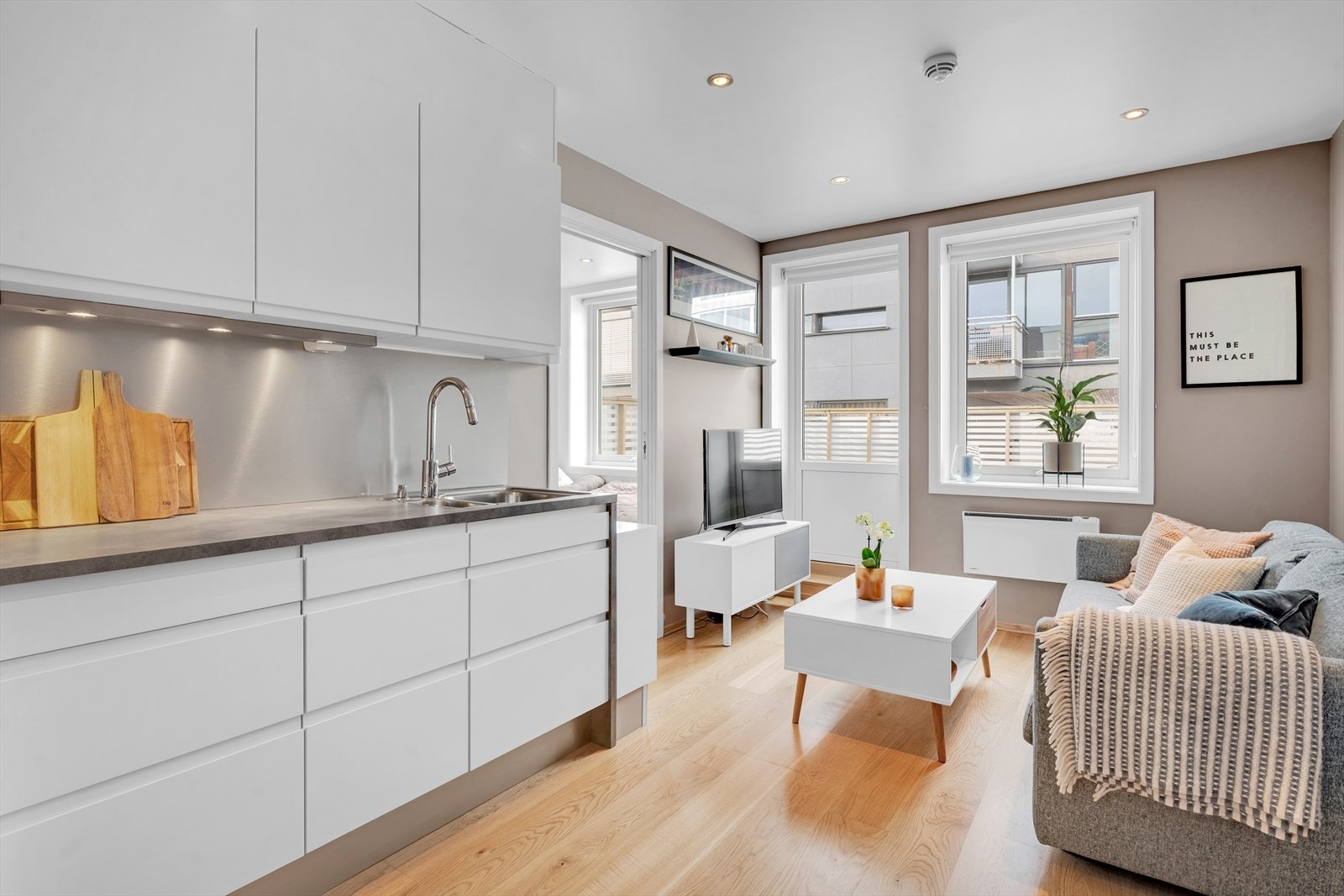 Stue og kjøkken i åpen løsning, som sikrer en sosial og trivelig atmosfære i leiligheten. Galleribilde