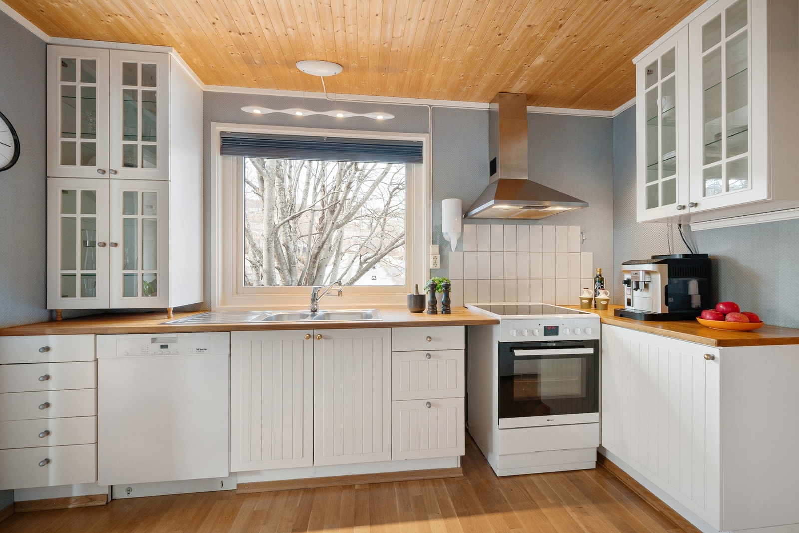 Takhøye overskap med glass gir et tiltalende uttrykk sammen med en flott benkeplate i heltre Galleribilde