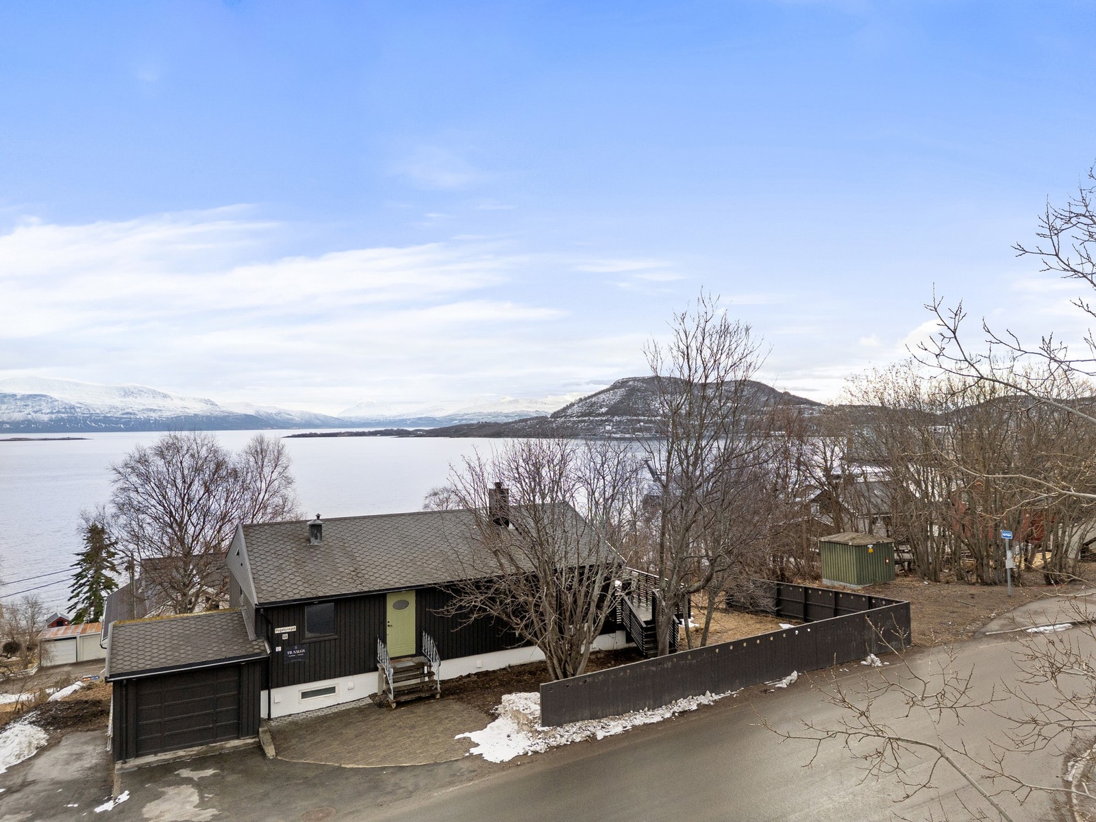 Eiendommen er pent opparbeidet og har gjerde/levegg mot gate, asfaltert gårdsplass og garasje Galleribilde