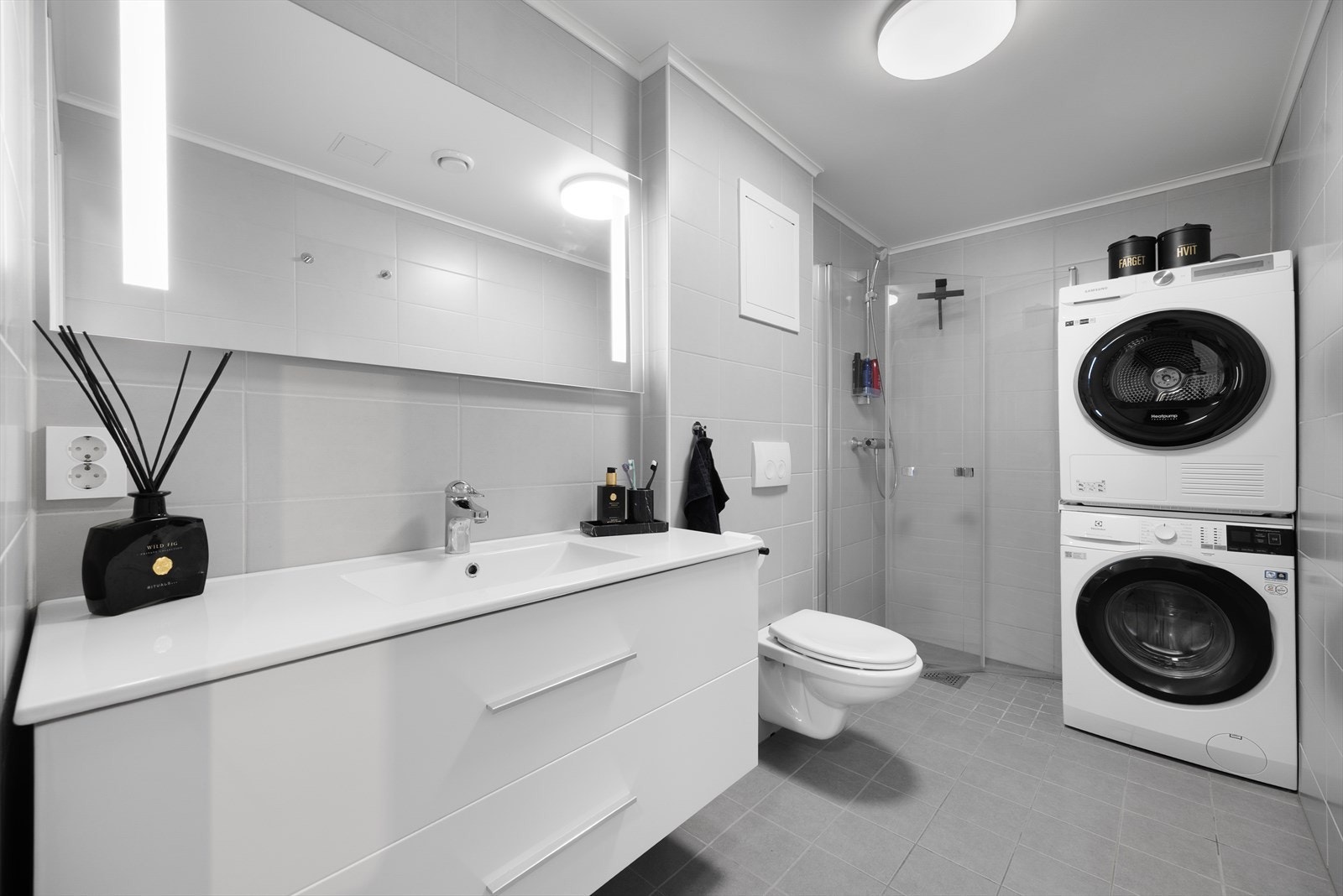 Badet er også innredet med dusjhjørne med innfellbare glassdører og veggmontert toalett. Badet fungerer også som vaskerom, med opplegg for og plass til vaskemaskin og tørketrommel. Galleribilde